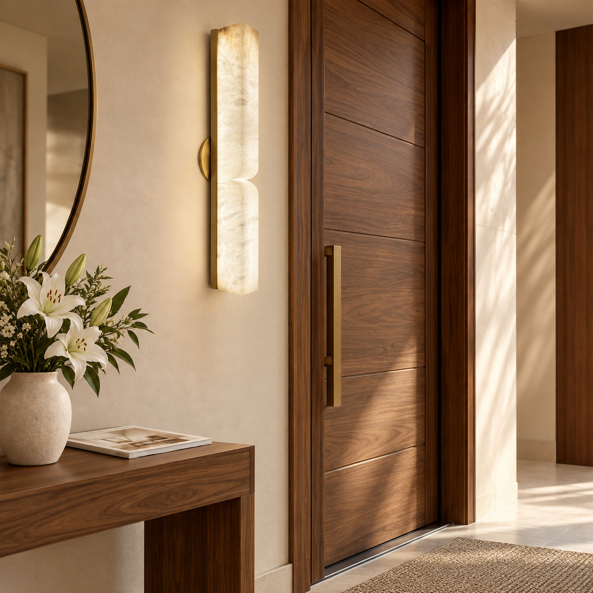 Illuminated vertical alabaster wall sconce mounted on entryway wall next to solid wood front door and console table
