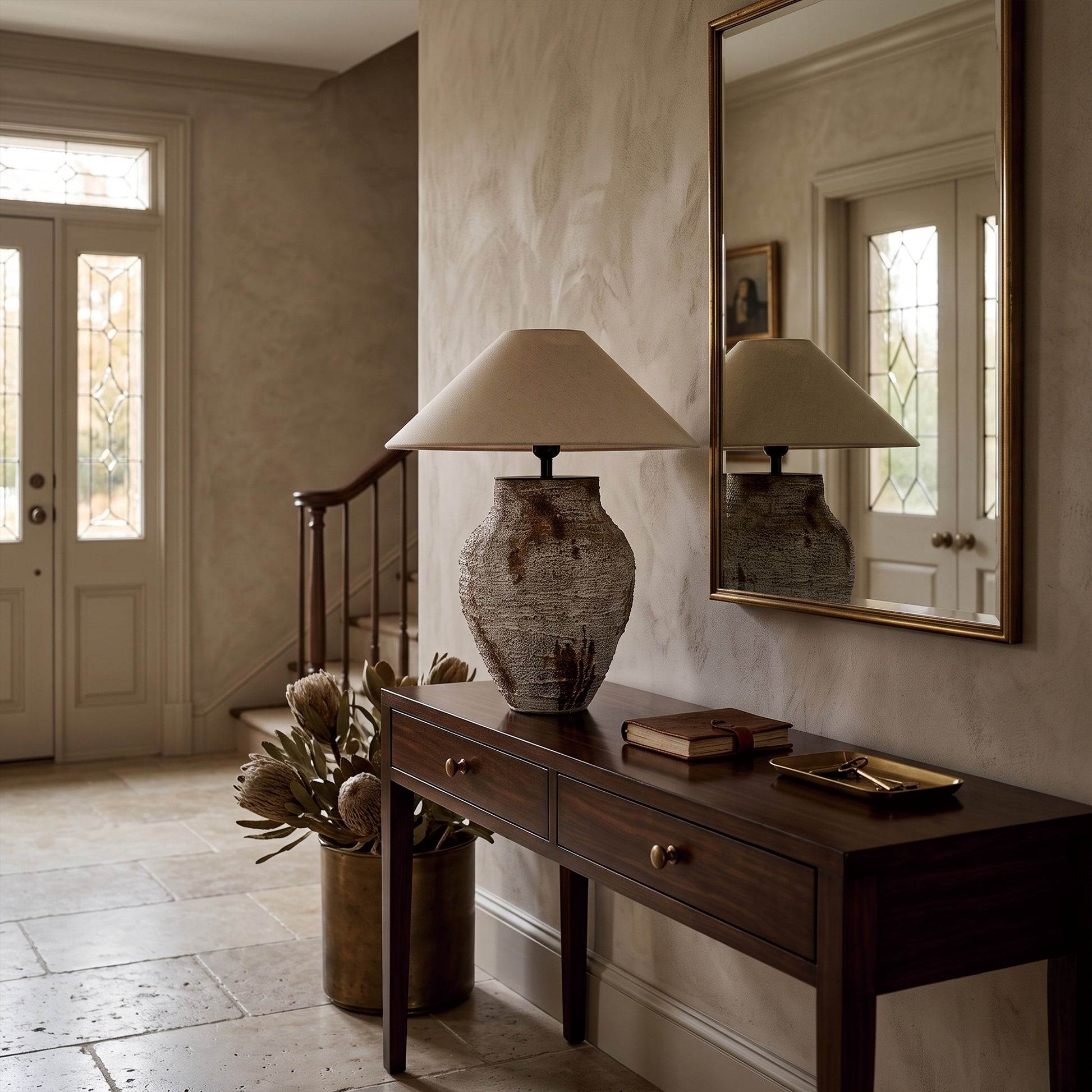 Antique style white ceramic table lamp on a dark wood entryway console table next to a wall mirror.