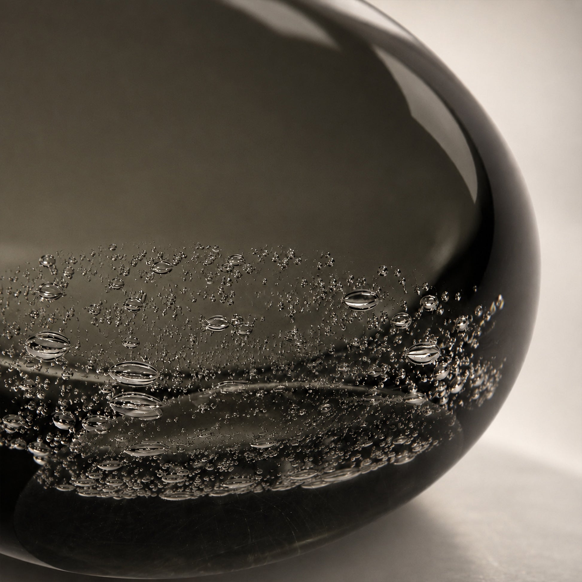 Close up of thick smoke gray art glass lamp base showing delicate embedded bubble texture details