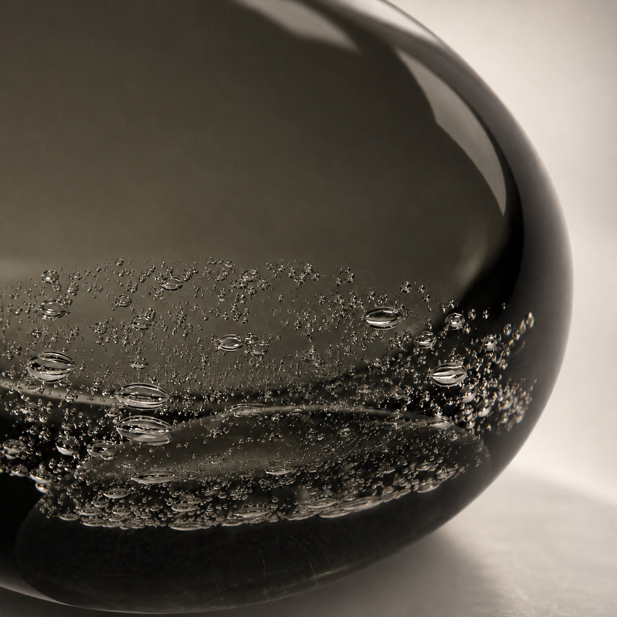 Close up of thick smoke gray art glass lamp base showing delicate embedded bubble texture details