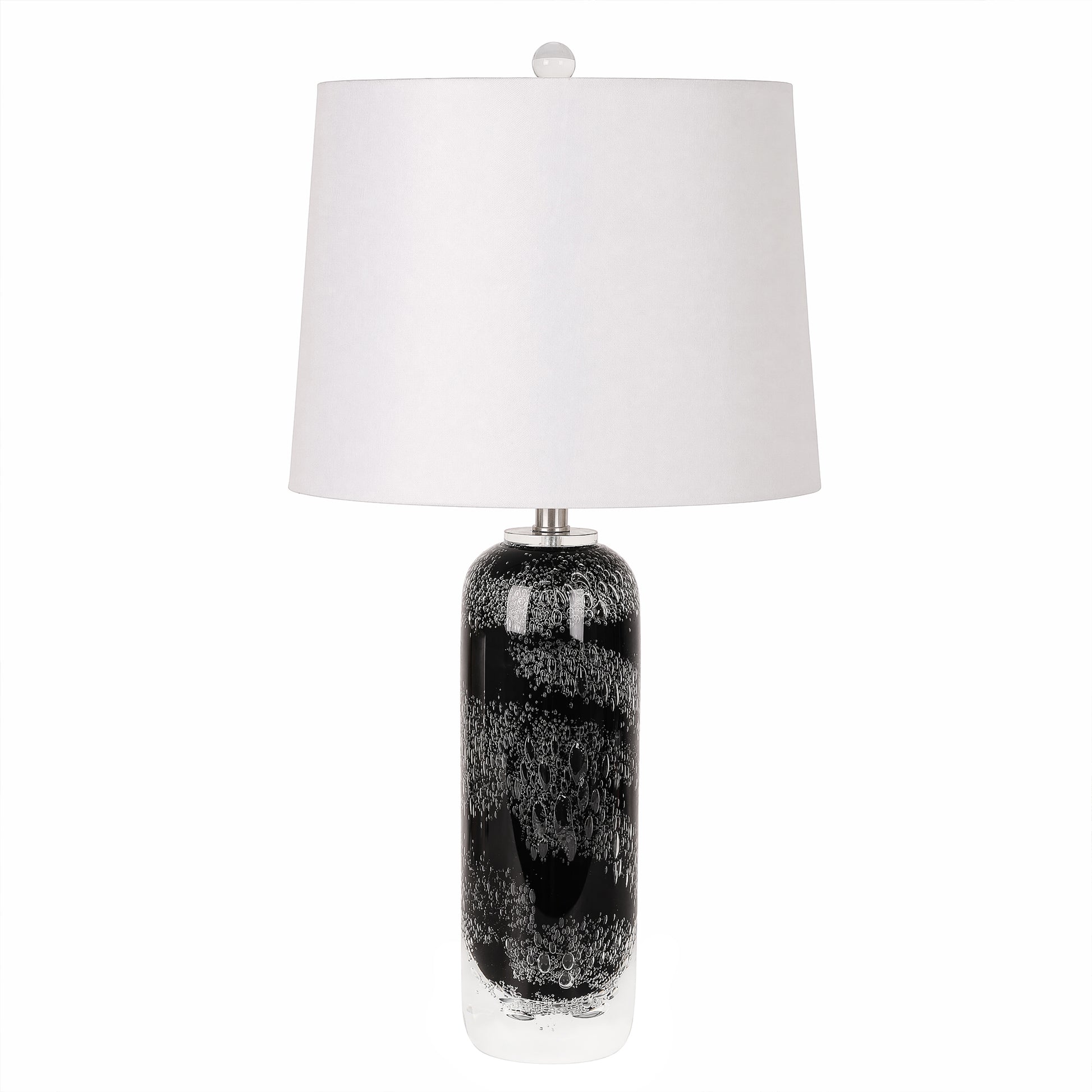 Art glass table lamp with black patterned seeded glass base and white drum lampshade turned off against a plain background.