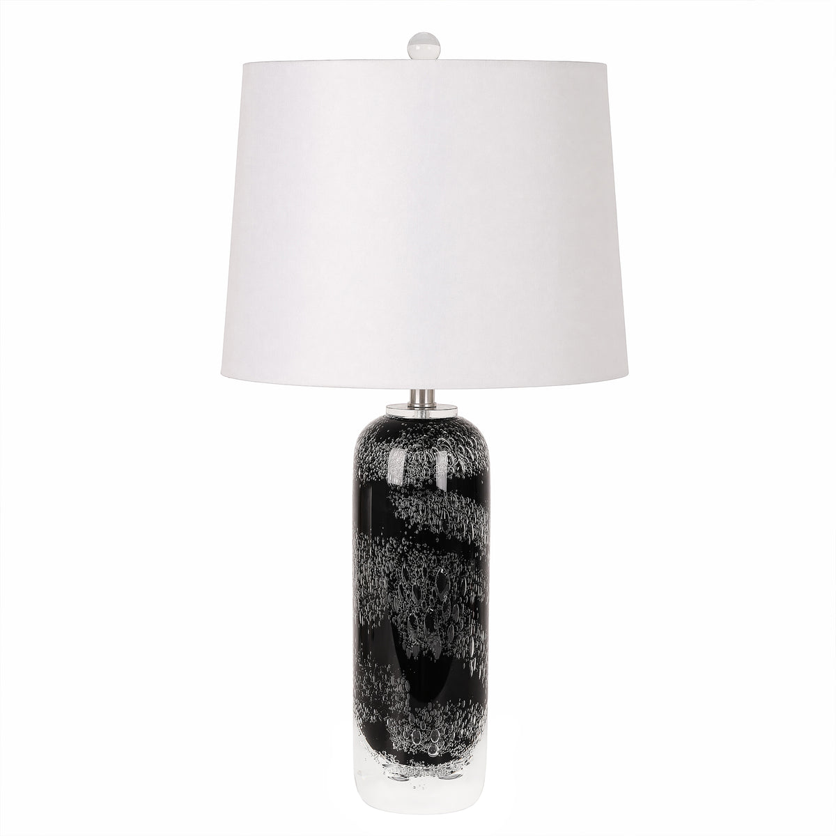 Art glass table lamp with black patterned seeded glass base and white drum lampshade turned off against a plain background.