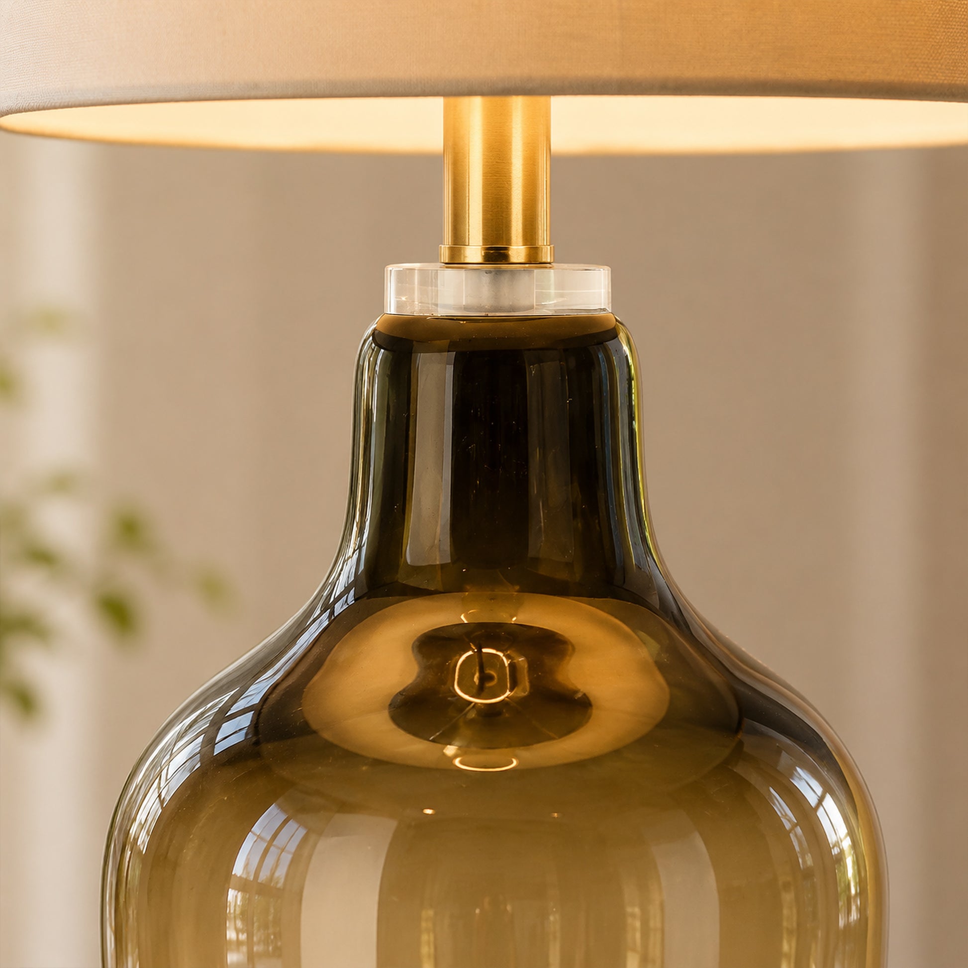 Close up detail of illuminated table lamp showing amber gradient glass body texture and brass socket