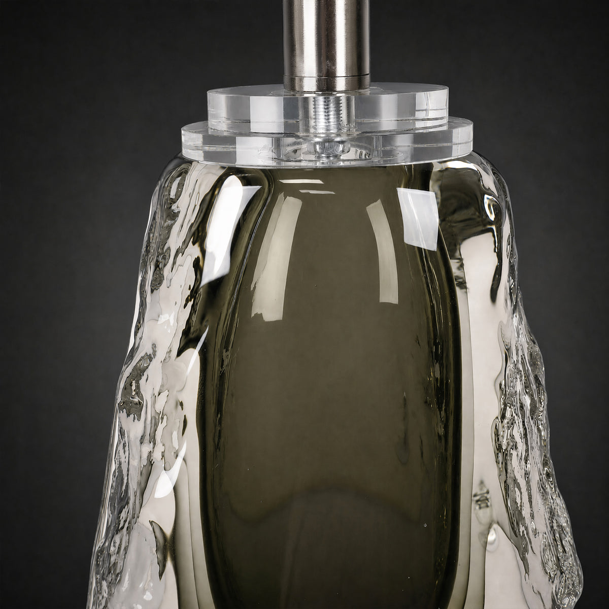 Close-up of the upper section of the glass lamp base showing solid clear acrylic connector and brushed metal stem.