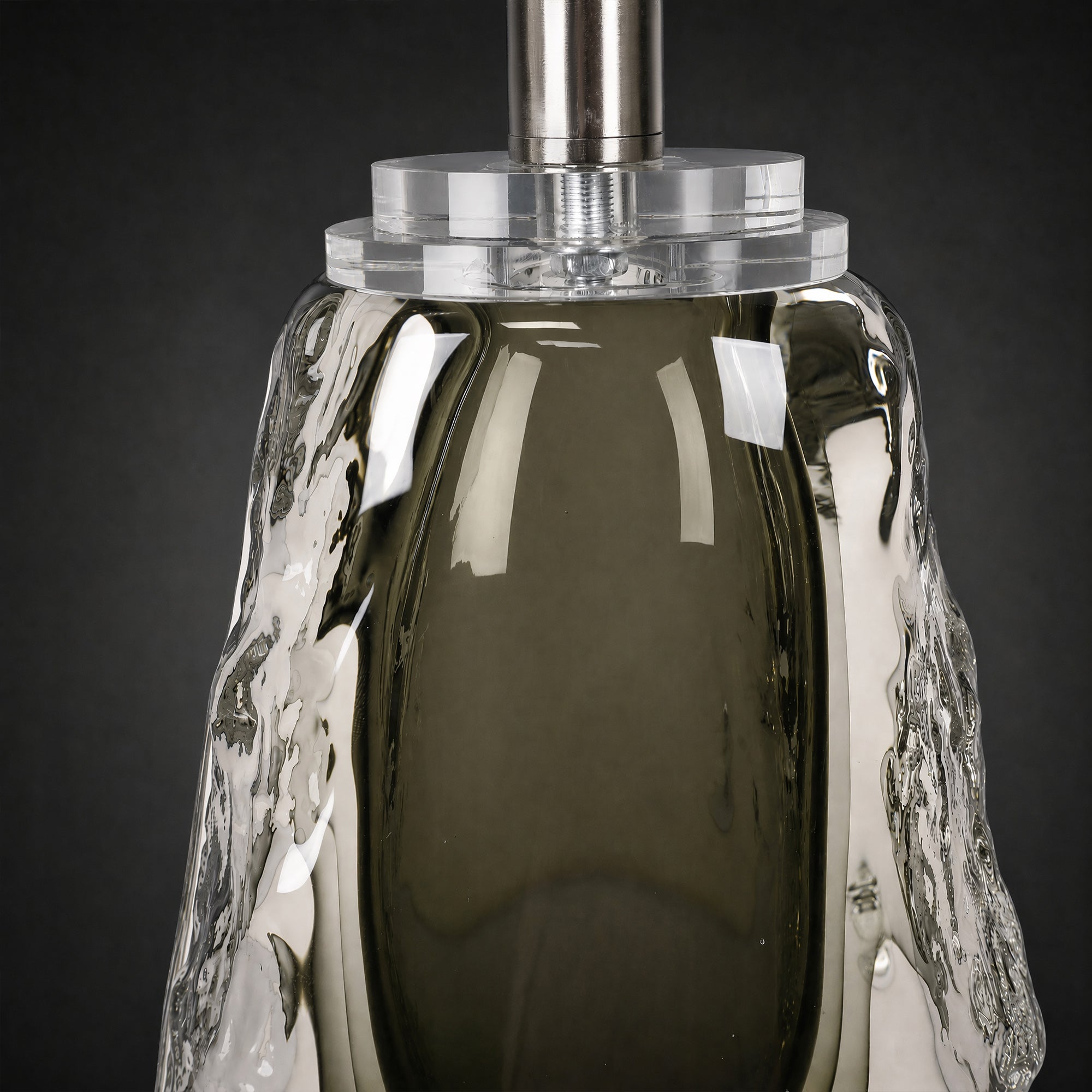 Close-up of the upper section of the glass lamp base showing solid clear acrylic connector and brushed metal stem.