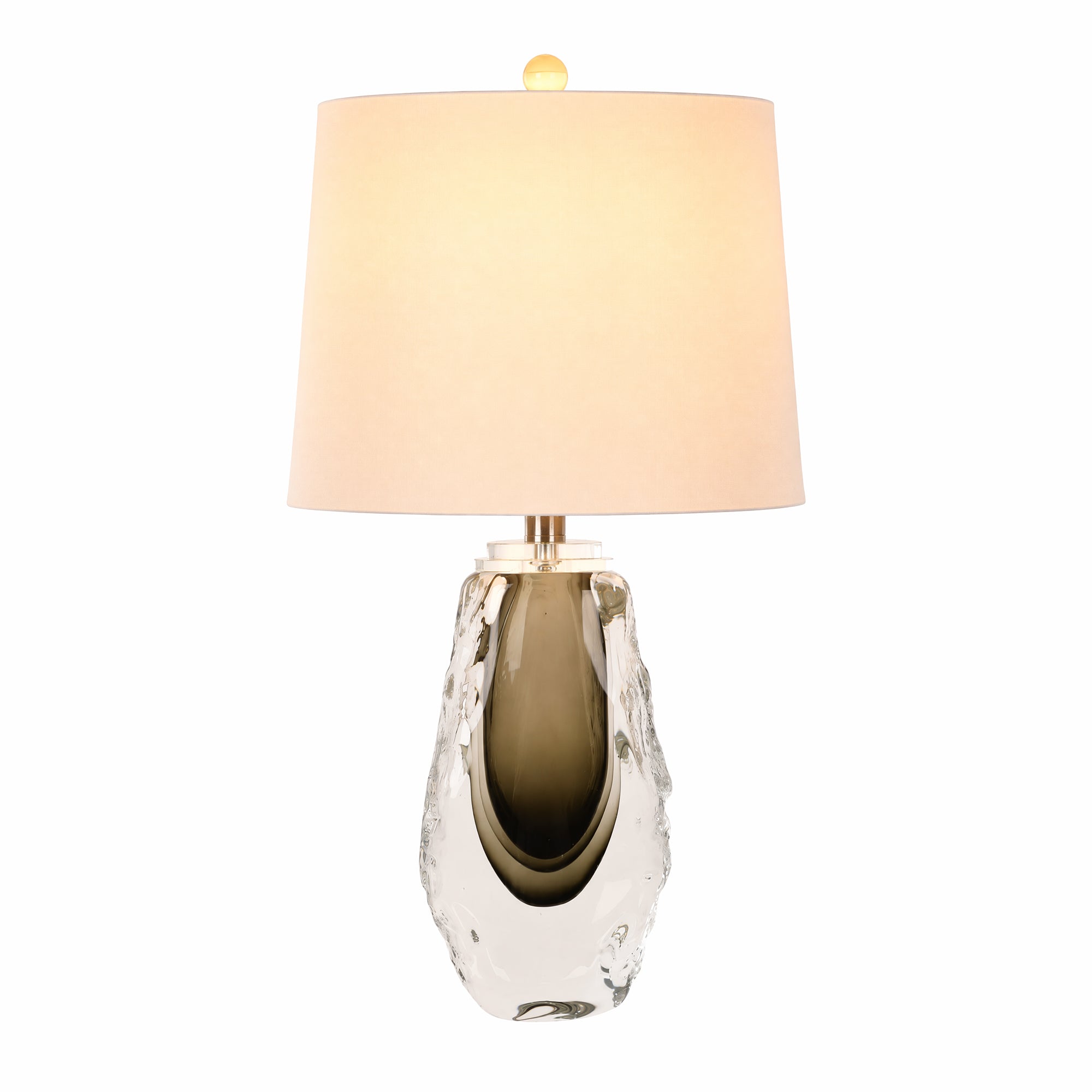 Illuminated art glass table lamp with a dark core ambient glowing through a cream fabric lampshade on a white background.