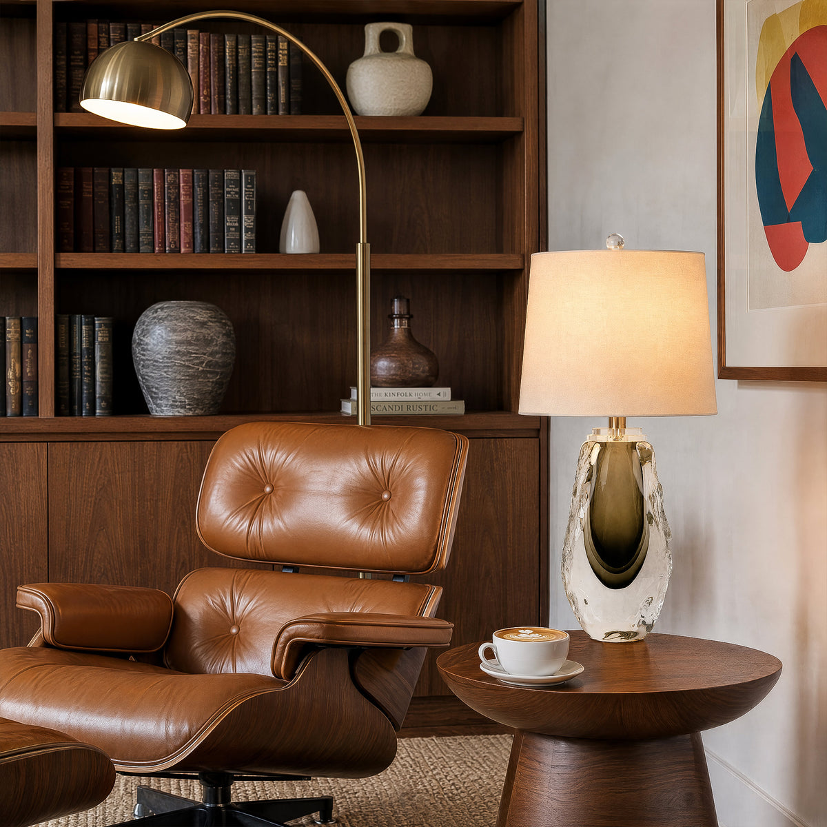 Art glass table lamp glowing next to a brown leather lounge chair and wooden side table in a cozy reading corner.