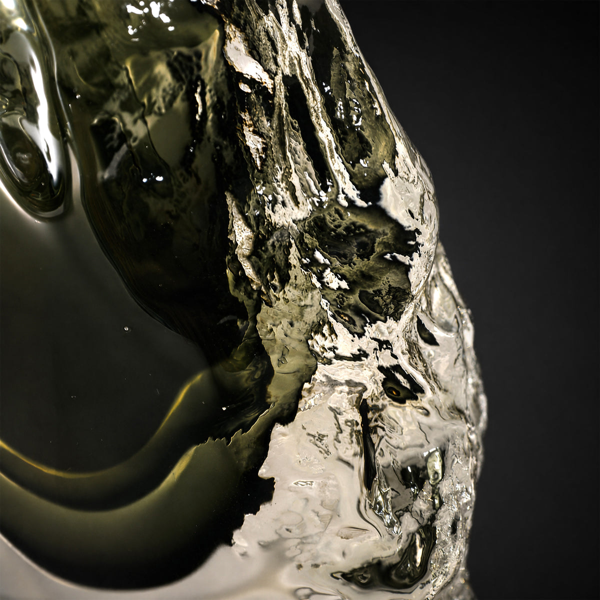 Detailed close-up showing the irregular rock-like texture and dark smoke green inner layer of the art glass lamp base.
