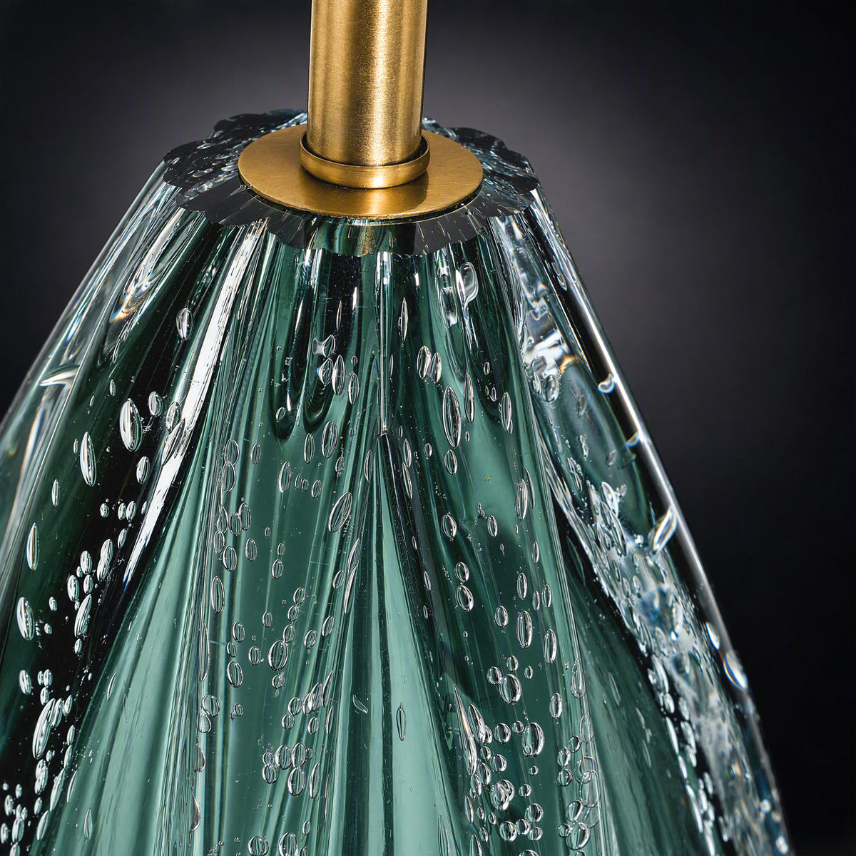 Close up detail of upper teardrop glass body featuring trapped inner bubbles, vertical ridges, and brass socket connector