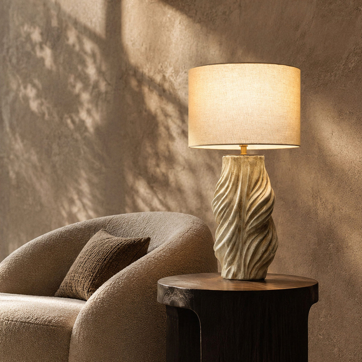 Artistic twisted ceramic table lamp illuminated on dark wooden side table beside cozy lounge chair