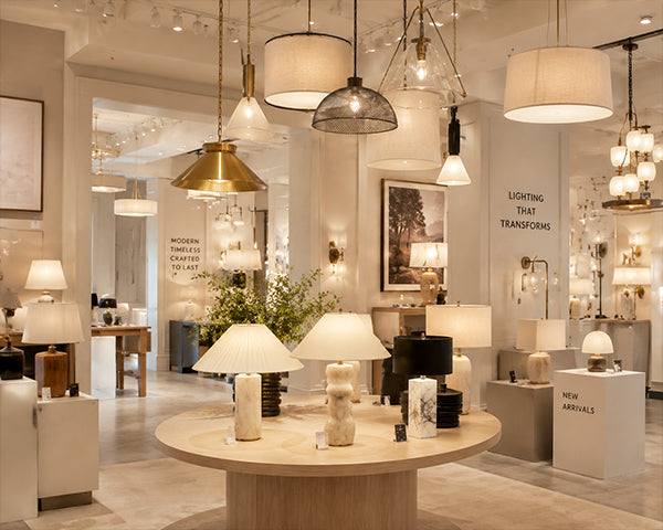 Luxury interior view of a moody showroom displaying an array of brushed brass pendants, alabaster sconces, and retro iron lamps from Auralumelamp Studio.