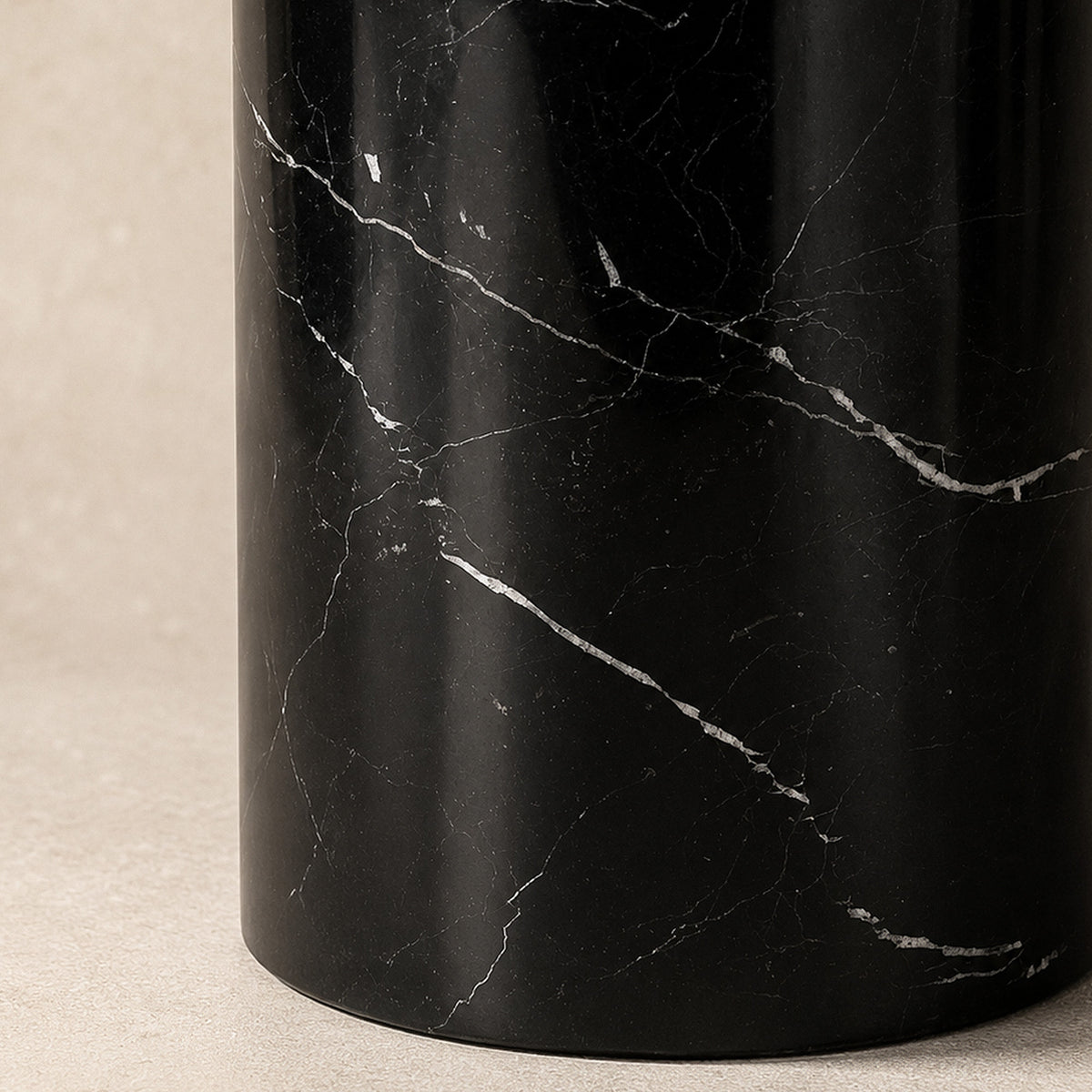 Close up detail of white veining patterns on polished black marble cylindrical table lamp base