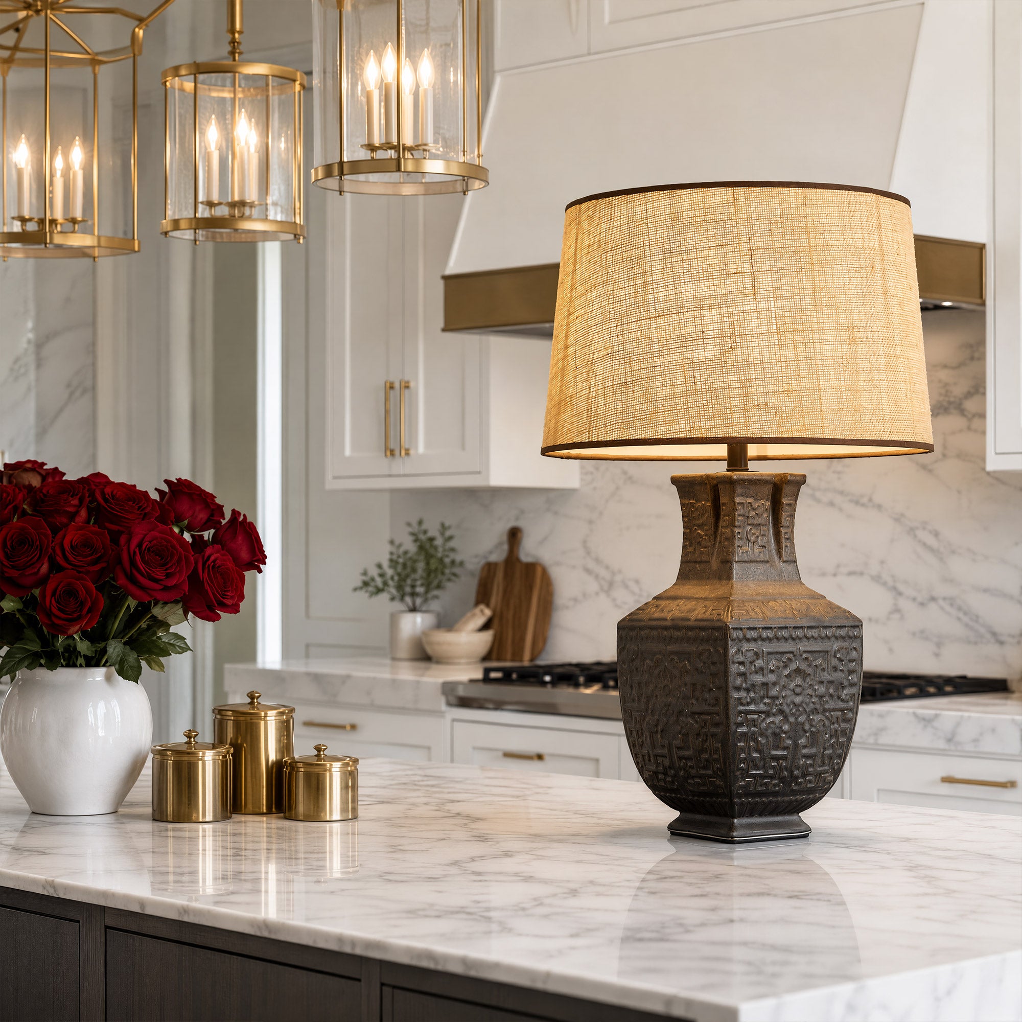 Illuminated artisan ceramic table lamp with burlap shade placed on a white marble kitchen island in a modern home