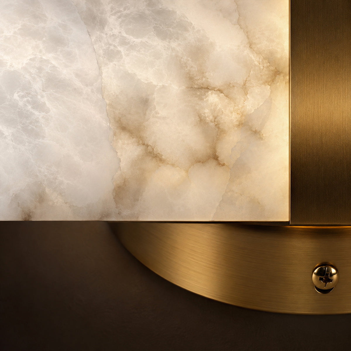 Macro close up detail of translucent natural alabaster stone grain texture joined by brushed solid brass metal band and screw