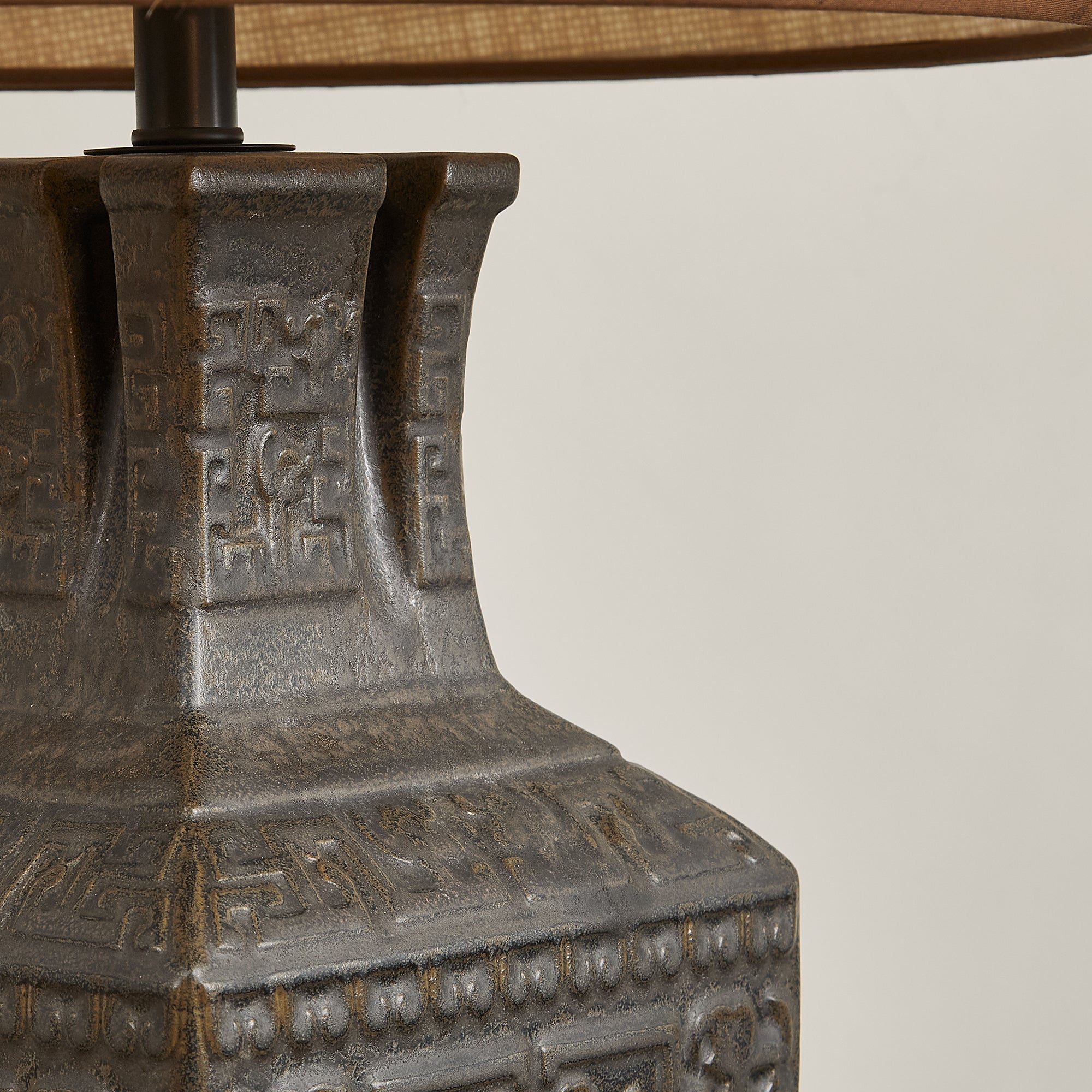 Close up detail of ceramic table lamp neck showing square vessel opening texture and vintage carved patterns