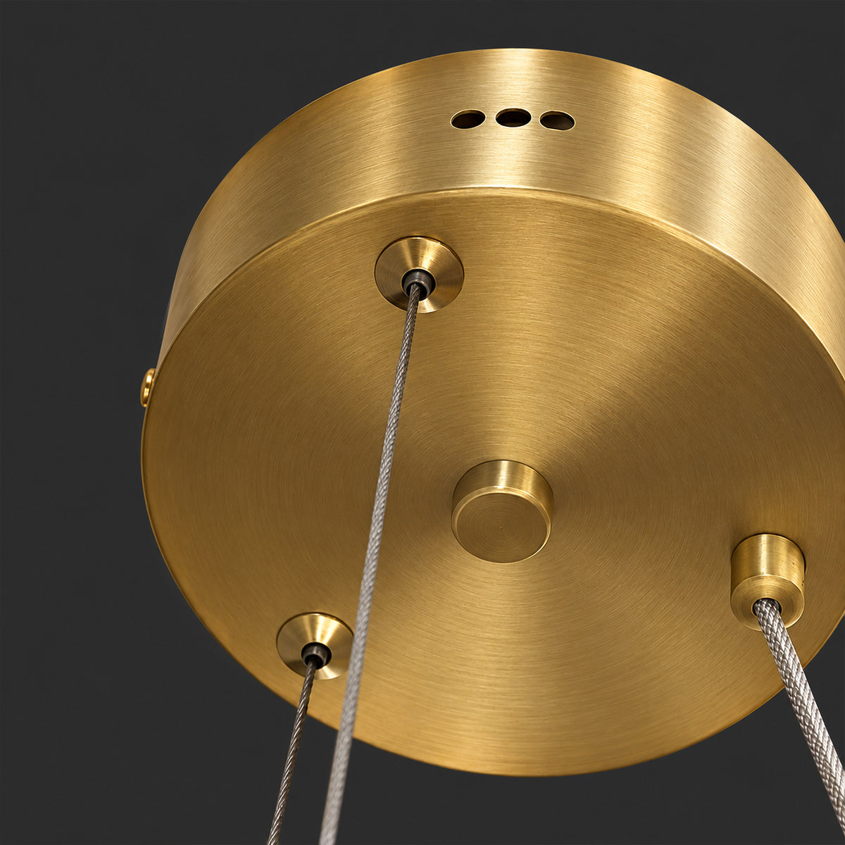 Close up view of brushed brass ceiling canopy with metallic suspension cables