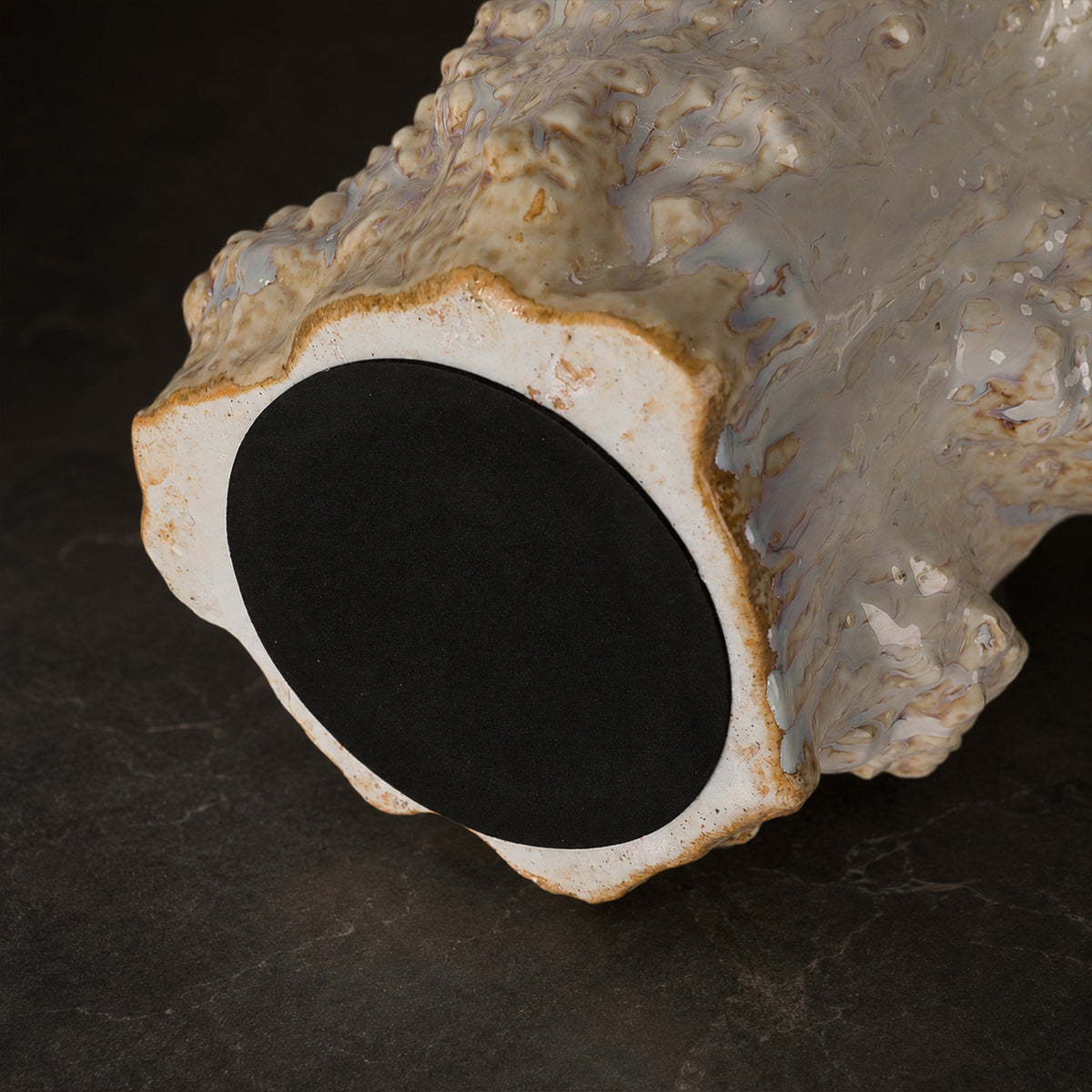 Detailed close up showing irregular sculpted bottom edge texture and black non slip felt pad of ceramic table lamp