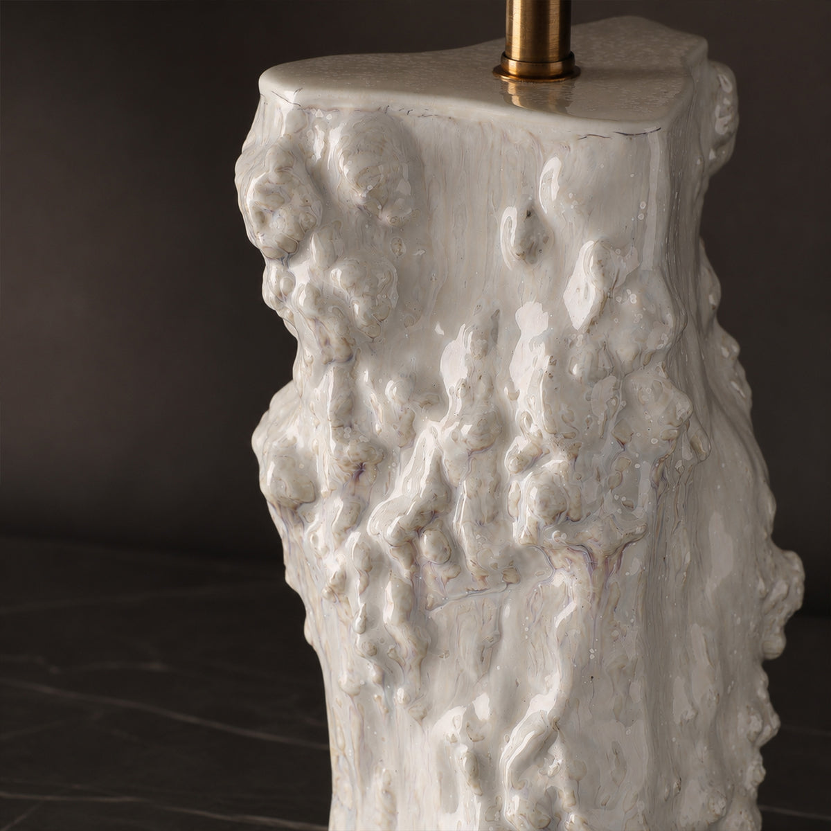 Close up view of glossy glazed organic rough texture and irregular sculpted edges on ceramic vessel table lamp body