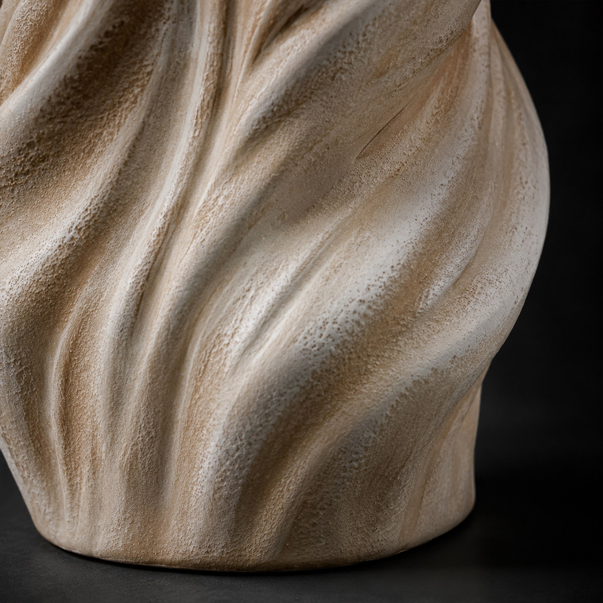 Close up view of the coarse textured finish and fluid spiral grooves on the white grey and brown ceramic lamp base