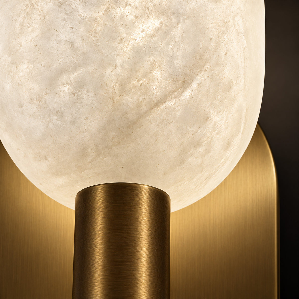 Extreme close up detail showing illuminated translucent Spanish natural alabaster stone grain and brushed solid brass metal base
