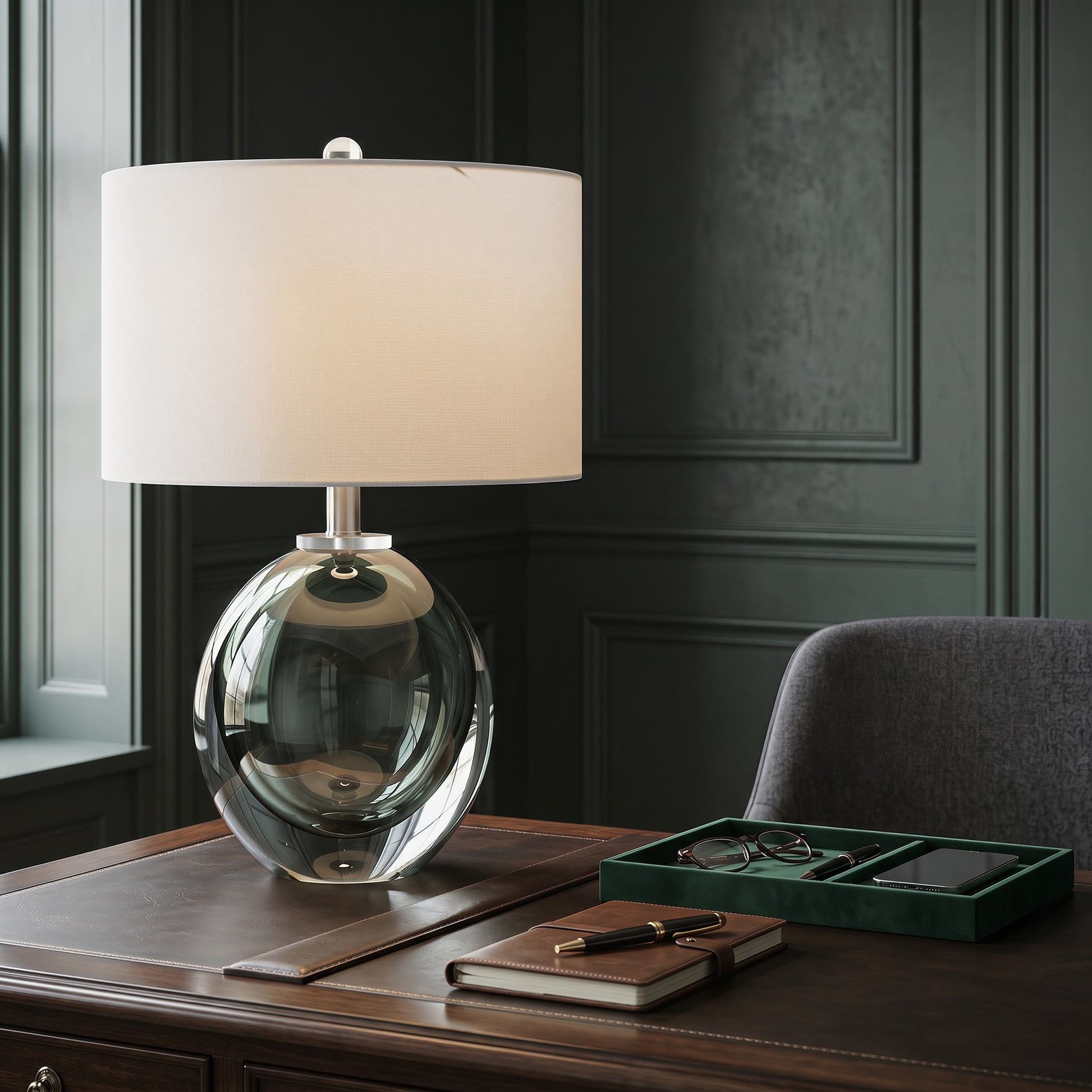 Close up view of dark green sphere glass table lamp with white shade on a dark leather executive study desk.