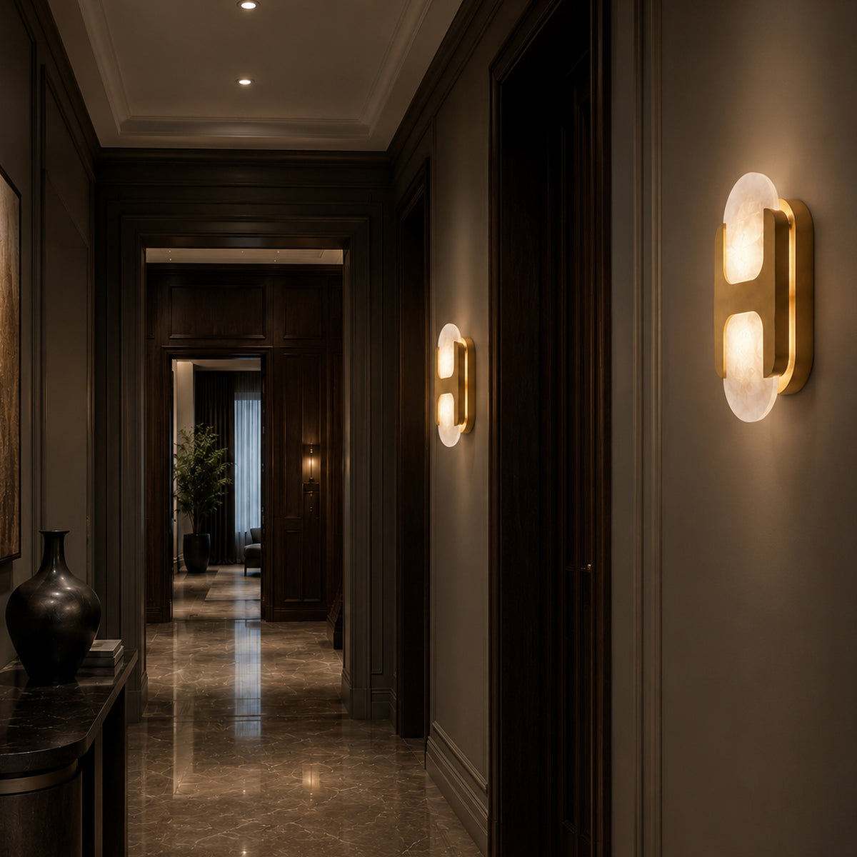 Multiple illuminated solid brass and Spanish alabaster wall sconces installed along a dark wood wall hallway interior