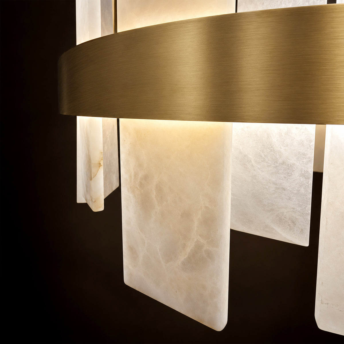 Detailed view of illuminated translucent alabaster slabs with natural cloud patterns and brushed brass metal frame