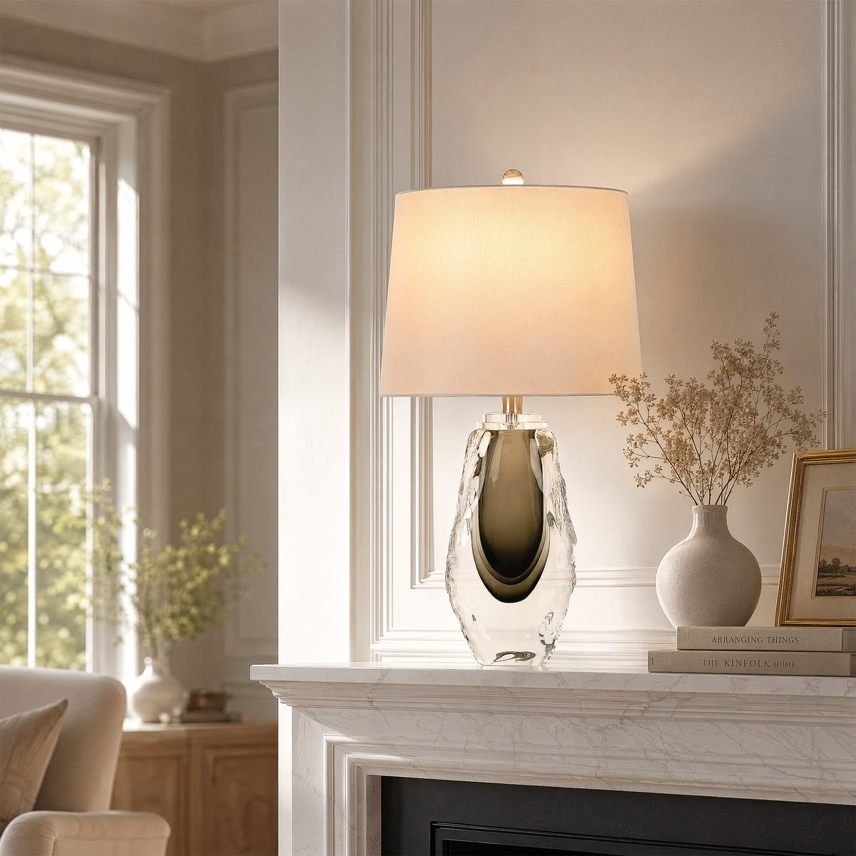 Art glass table lamp illuminated on a marble fireplace mantel in an entryway living room corner.