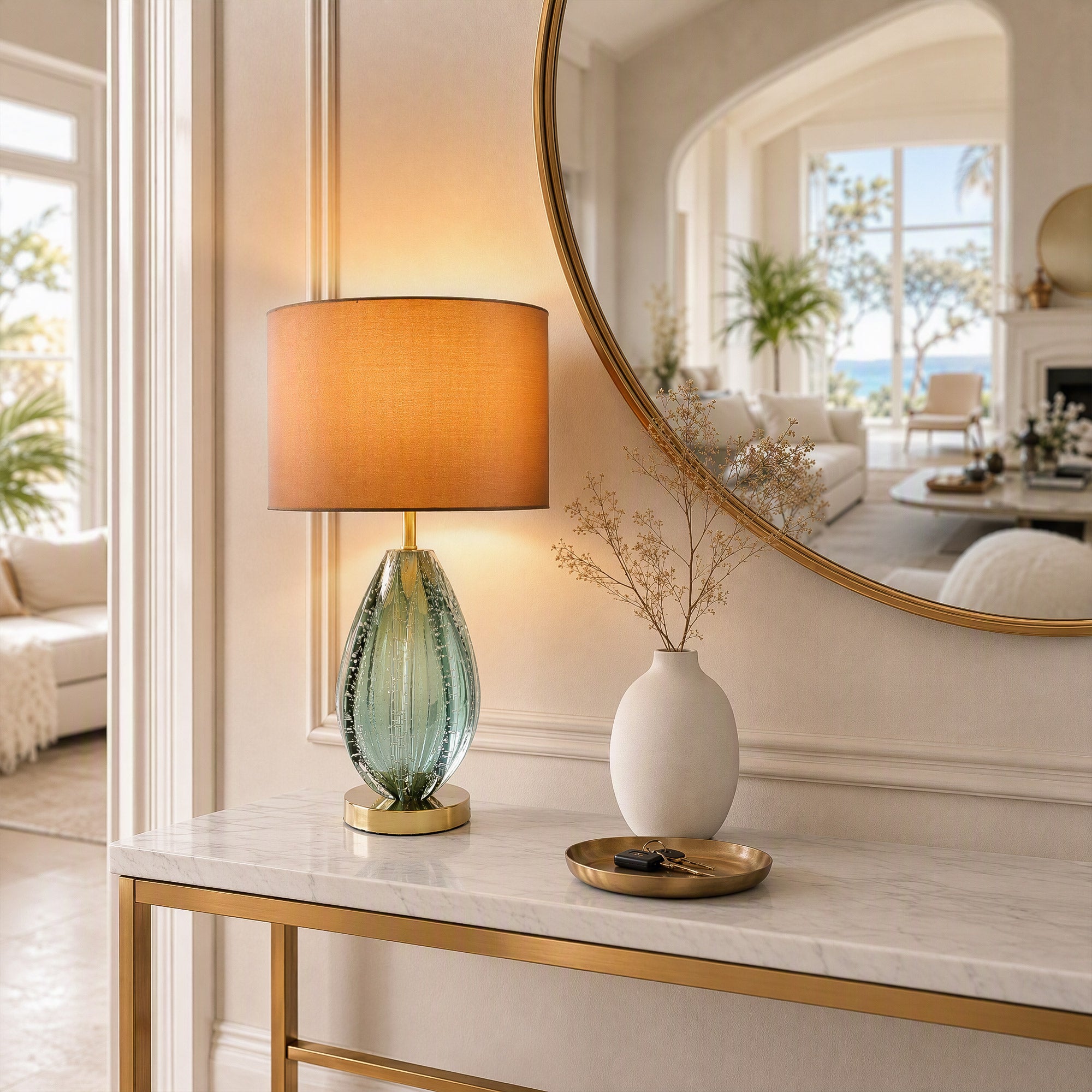 Illuminated art glass table lamp on white marble console table with gold legs in elegant entryway foyer