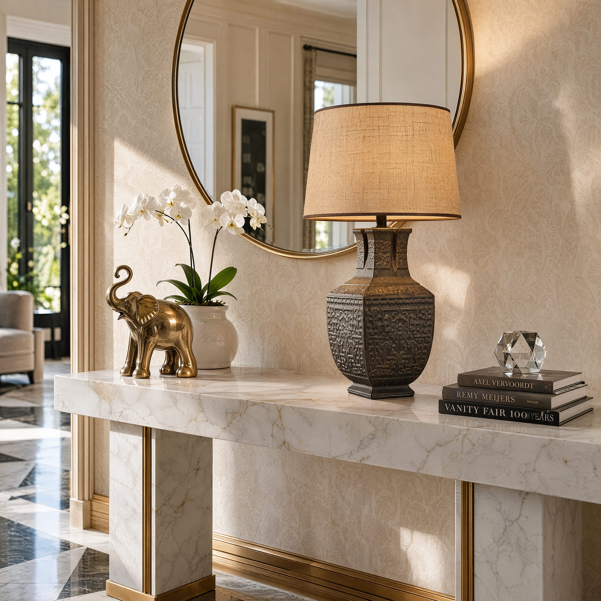 Illuminated vintage ceramic table lamp on a white marble console table in a luxury entryway near a round gold mirror