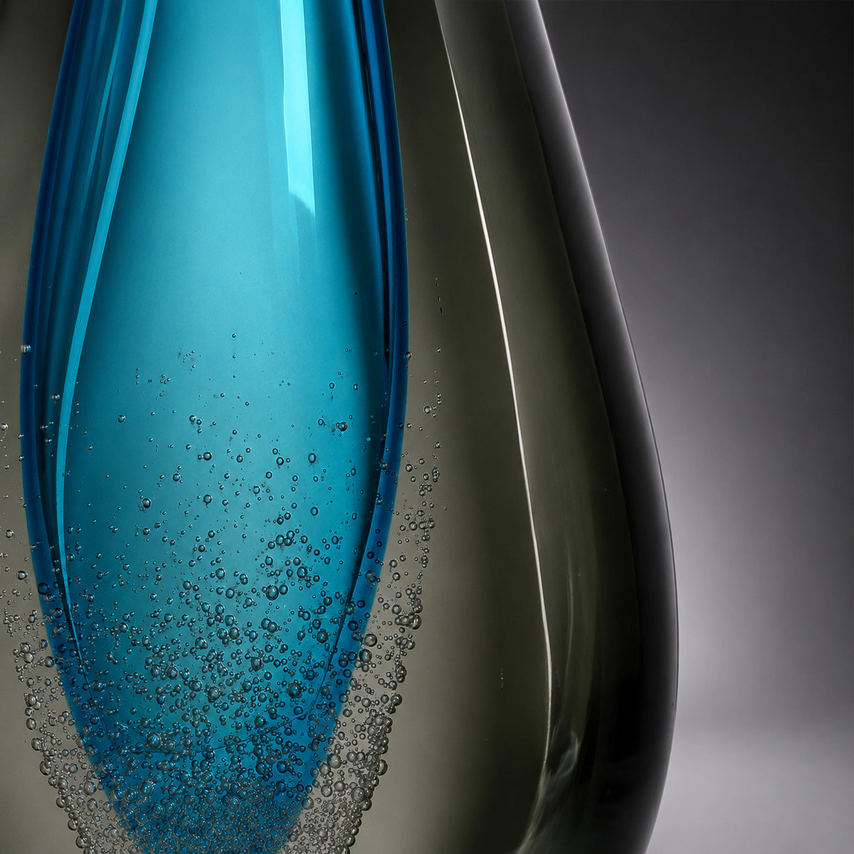 Detailed view of curved glass lamp base displaying rich contrast between ocean blue and smoke grey tones