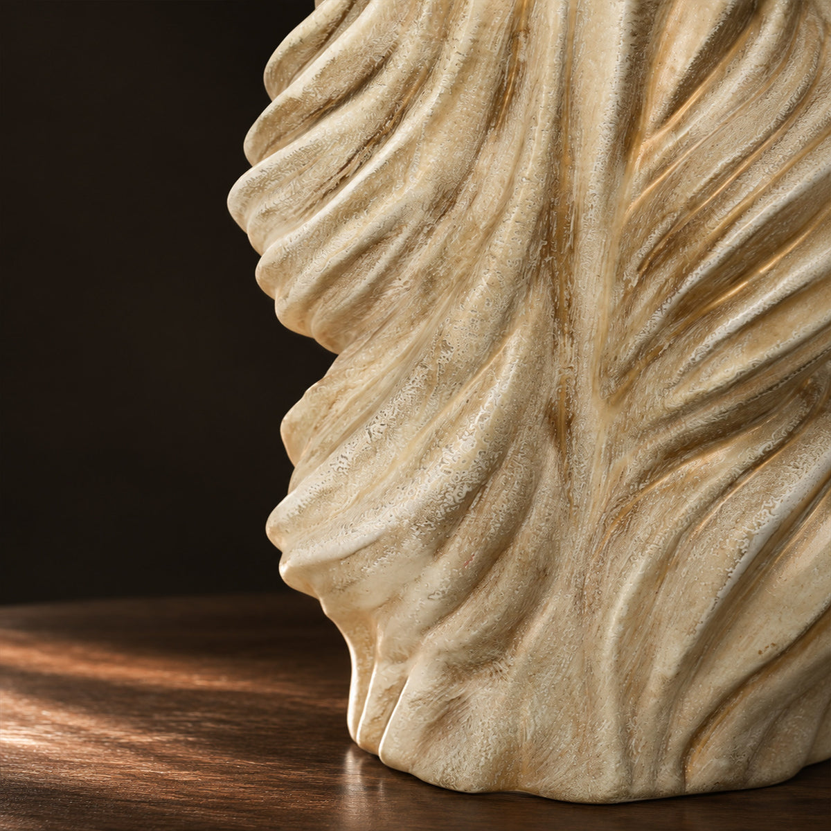 Close up view of artisanal matte textured twisted ceramic lamp base on dark wooden surface