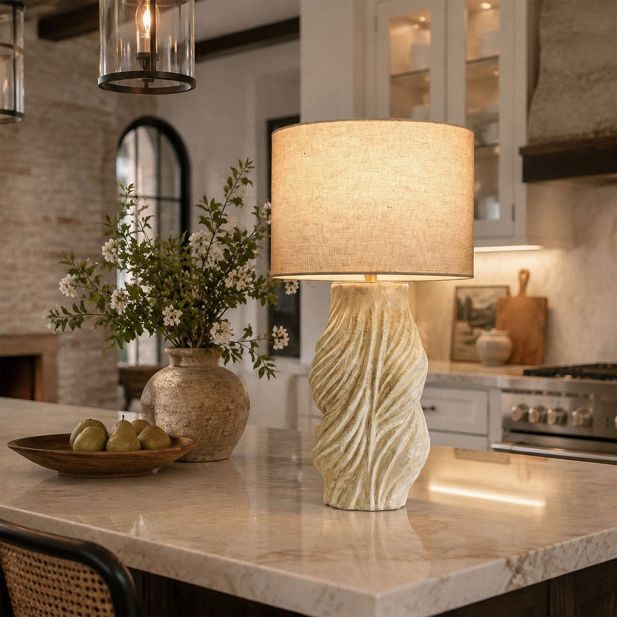 Close up view of illuminated vintage twisted ceramic table lamp on marble kitchen island counter