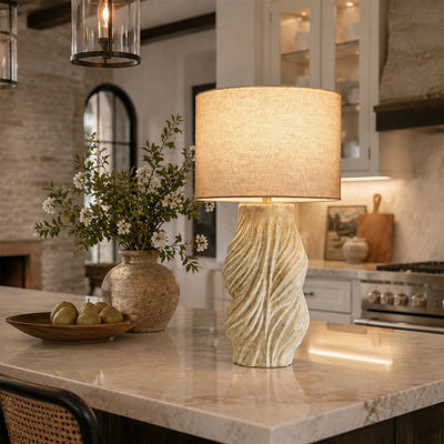 Close up view of illuminated vintage twisted ceramic table lamp on marble kitchen island counter