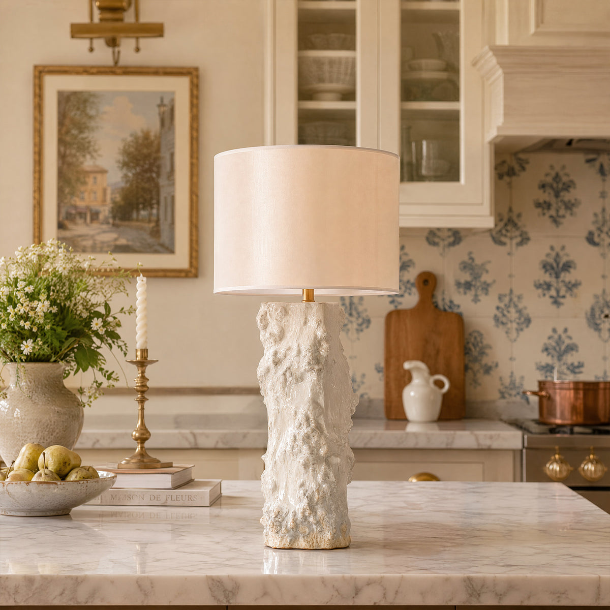 Organic textured white ceramic vessel table lamp placed on marble kitchen island in elegant French country kitchen