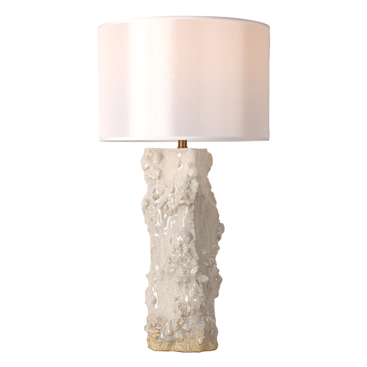 Warmly glowing handmade vintage organic textured ceramic vessel table lamp with white drum shade on white background