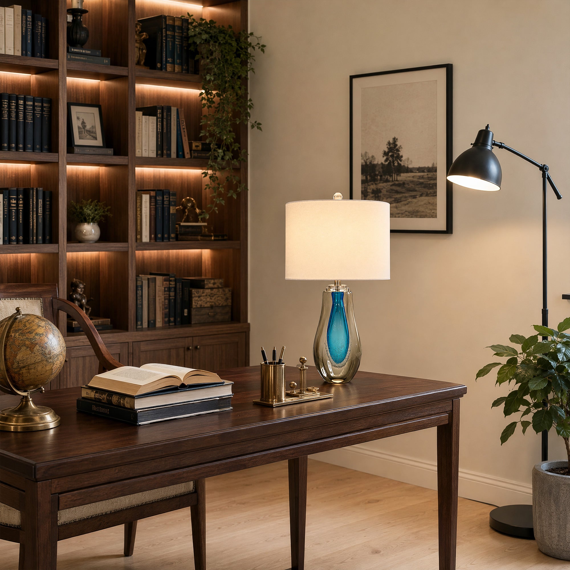 Art glass table lamp emitting warm light on a rich dark wood desk in an elegant home office