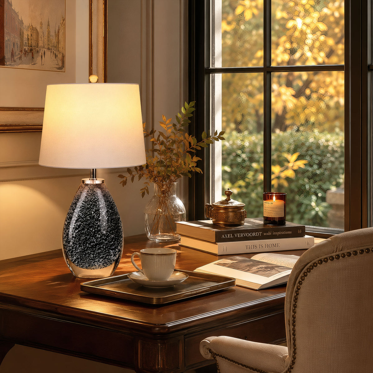 Illuminated black snowflake glass table lamp providing cozy warm lighting on a wooden study desk by the window.