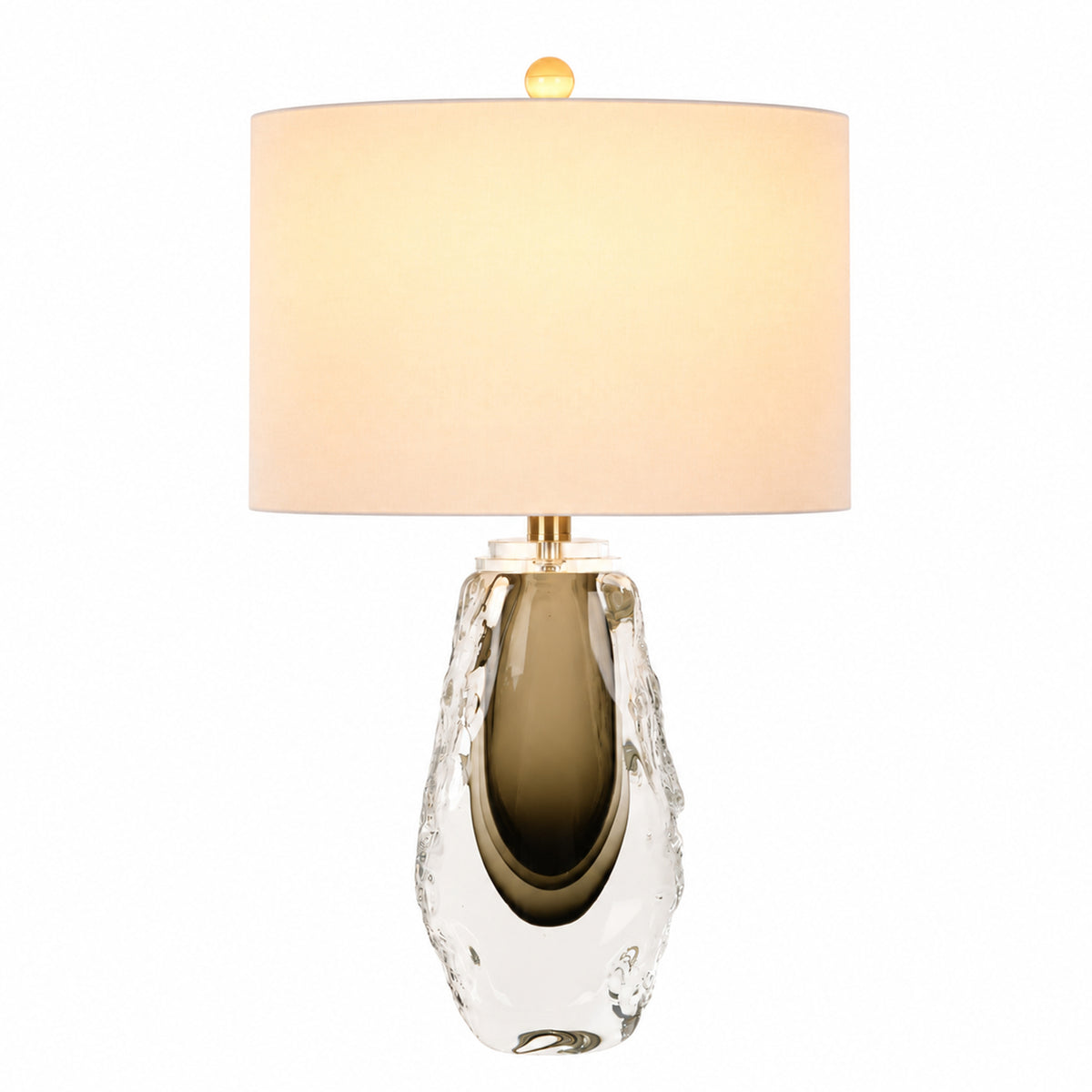 Warm illuminated artisanal glass table lamp with brass hardware smoke gray inner base and white shade on white background