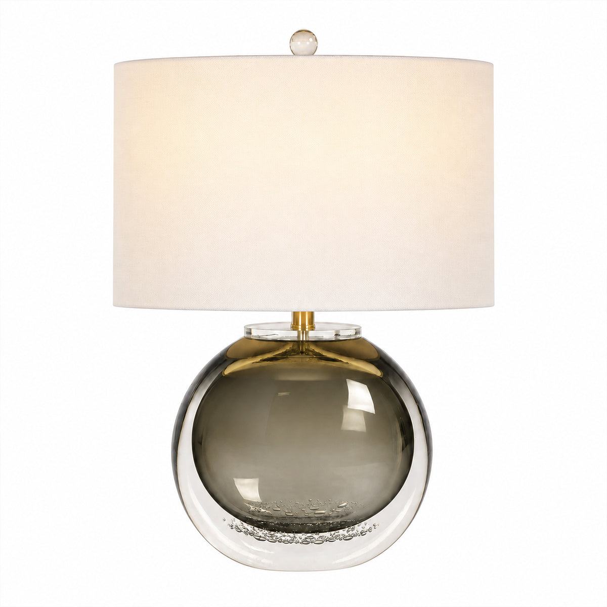 Warm illuminated smoke gray glass table lamp with brass hardware and white shade on white background
