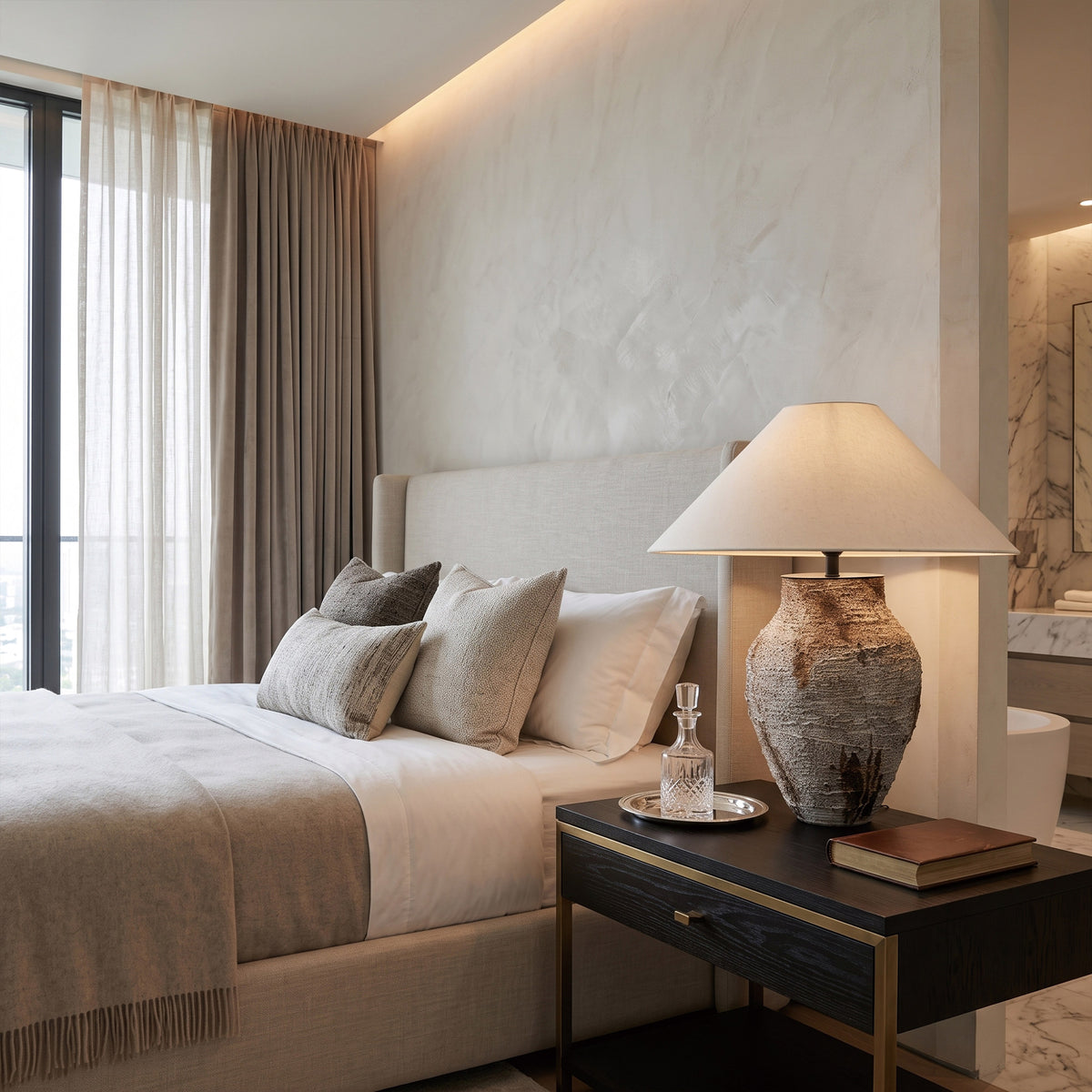 Illuminated vintage white ceramic table lamp casting a soft warm glow in a luxury modern bedroom interior.