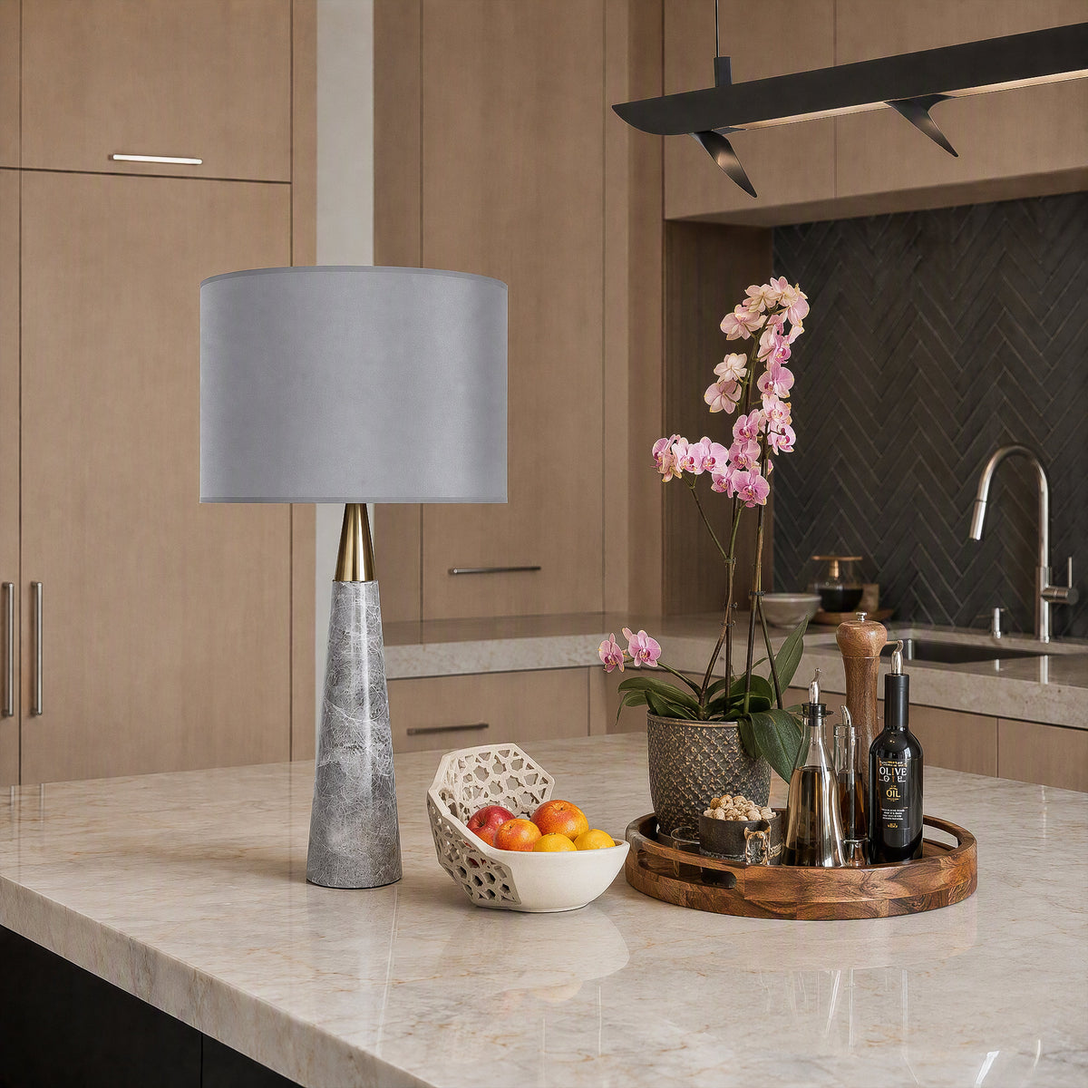 Unlit grey marble cone table lamp on white marble kitchen island counter beside wooden tray