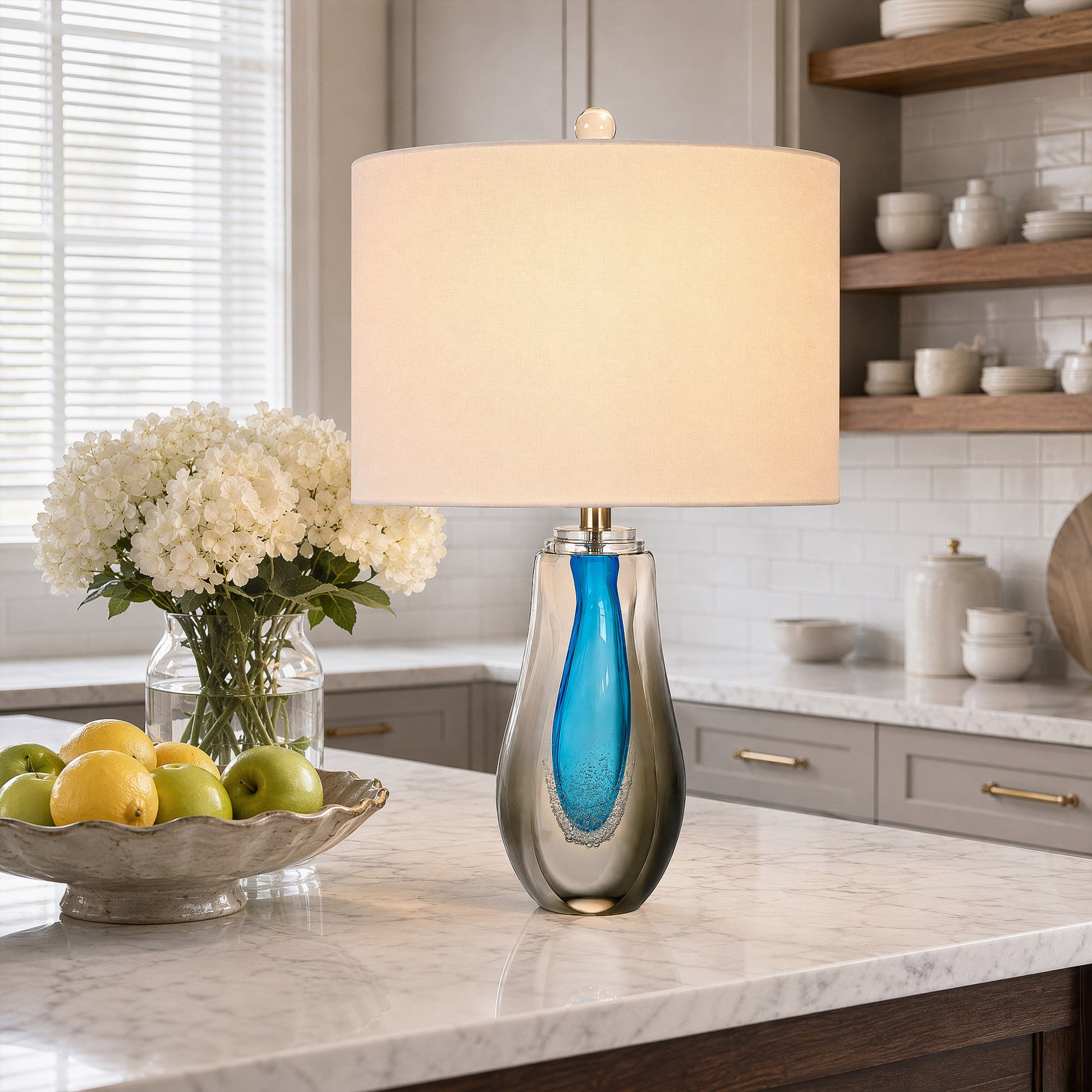 Illuminated art glass table lamp on a marble kitchen island counter with fresh flowers