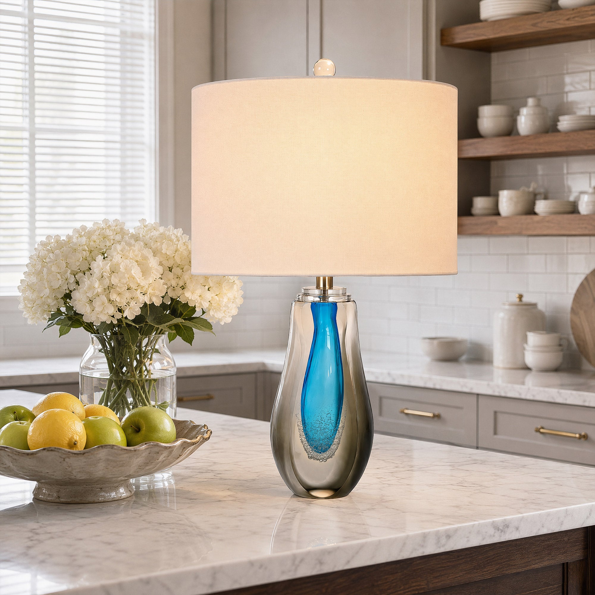 Illuminated art glass table lamp on a marble kitchen island counter with fresh flowers