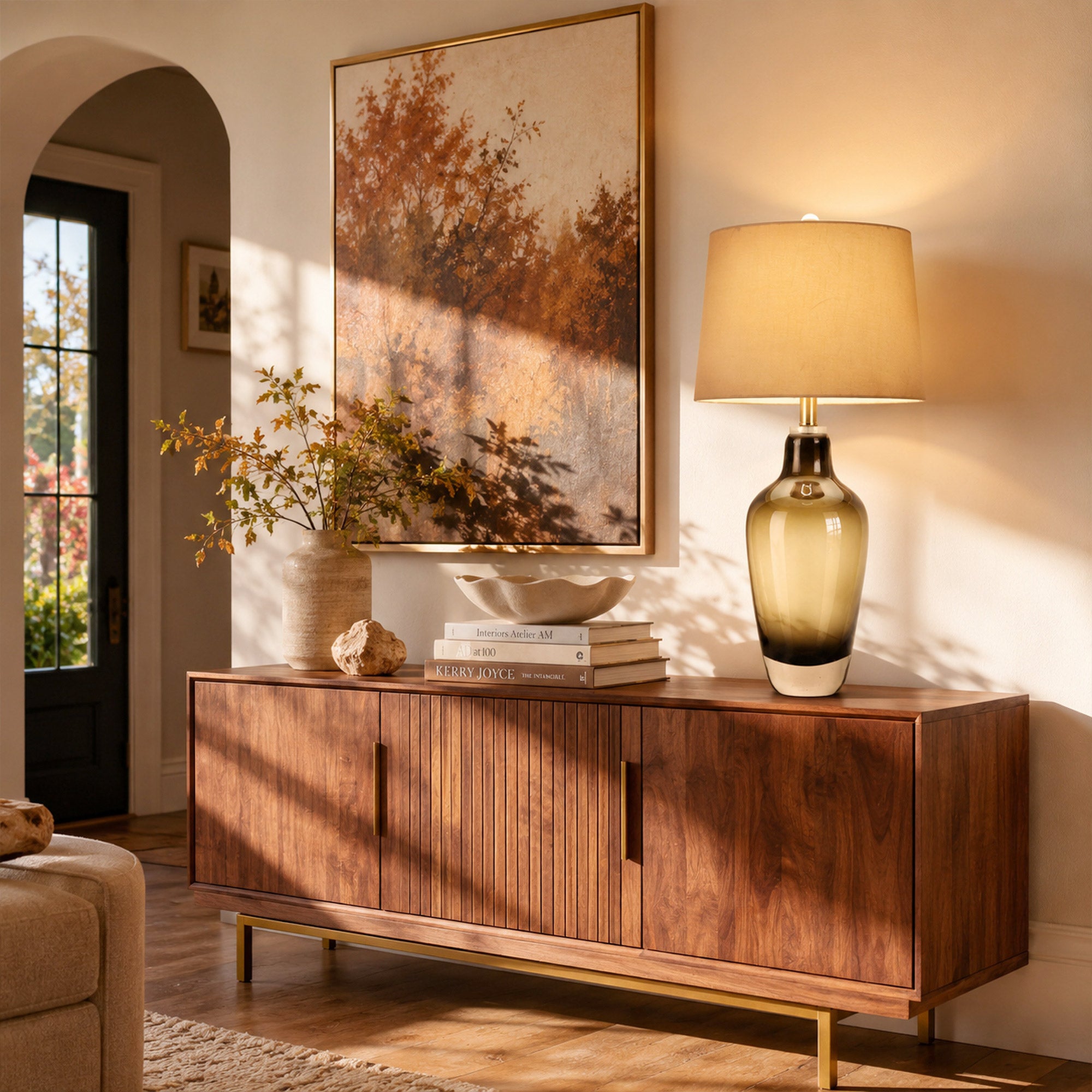 Illuminated art glass table lamp on wooden sideboard credenza in living room with warm afternoon sunlight