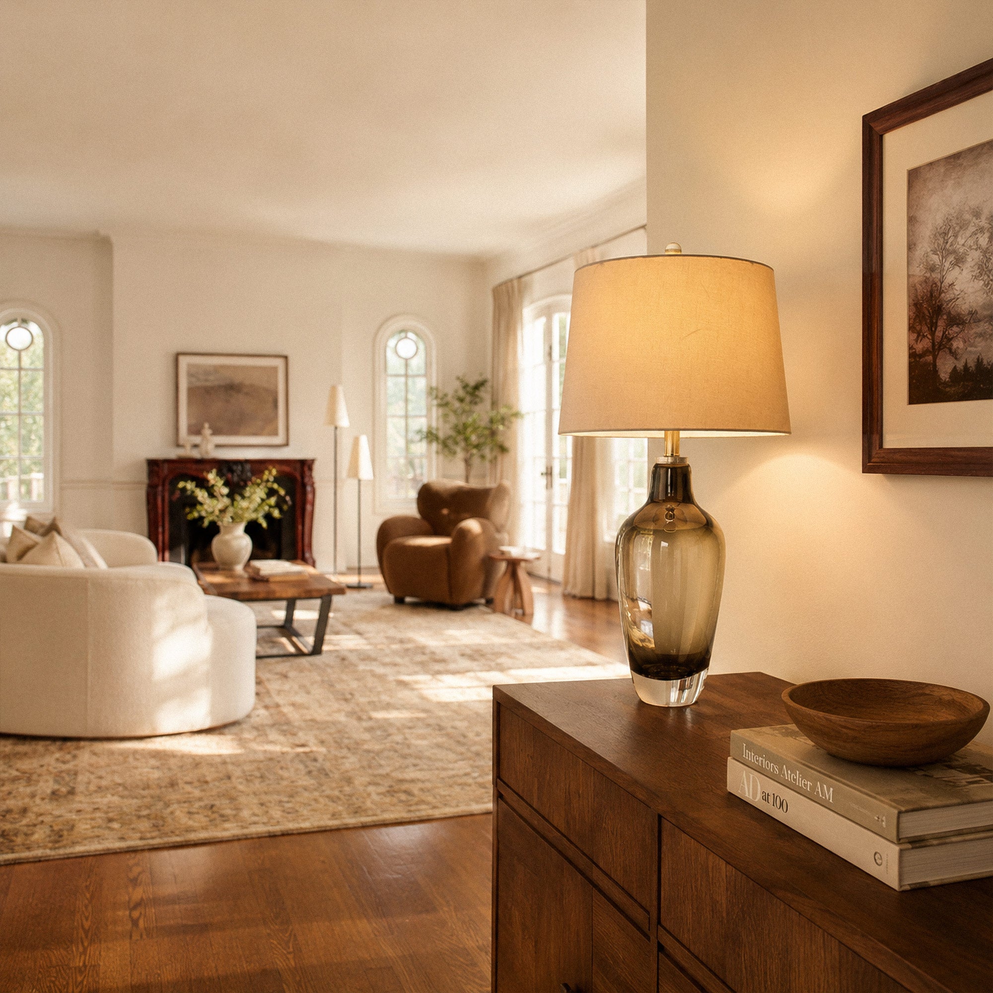 Illuminated amber gradient glass table lamp on wooden cabinet near entrance overlooking living room