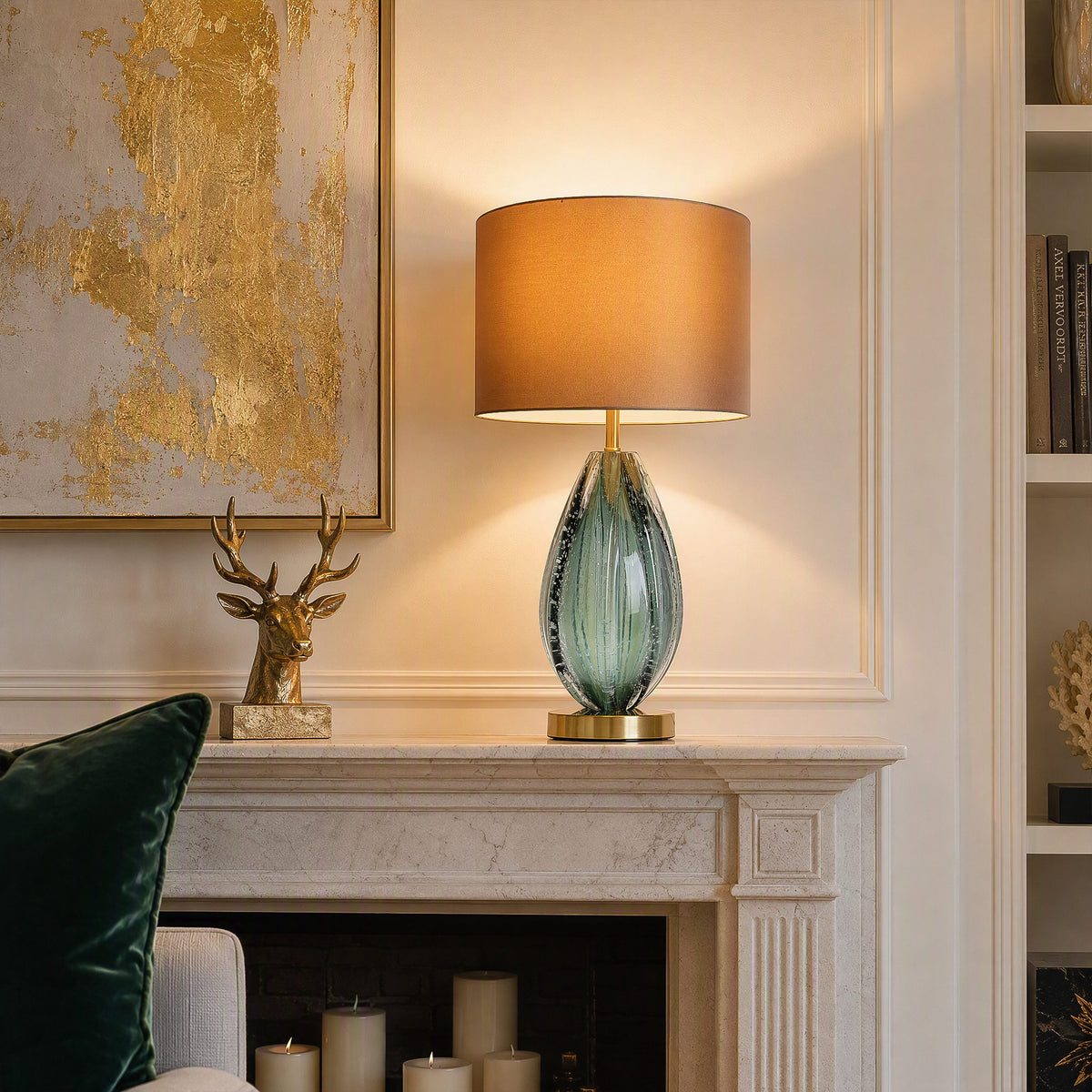 Illuminated teal art glass table lamp on fireplace mantel next to brass deer figurine in warm living room