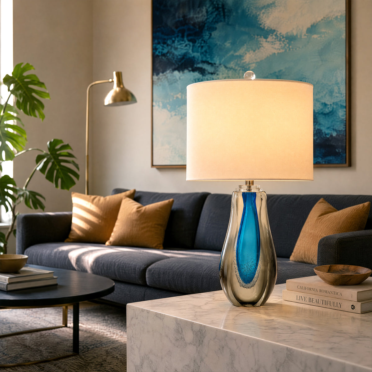 Warm lit art glass table lamp placed on a marble side table in a stylish living room setting