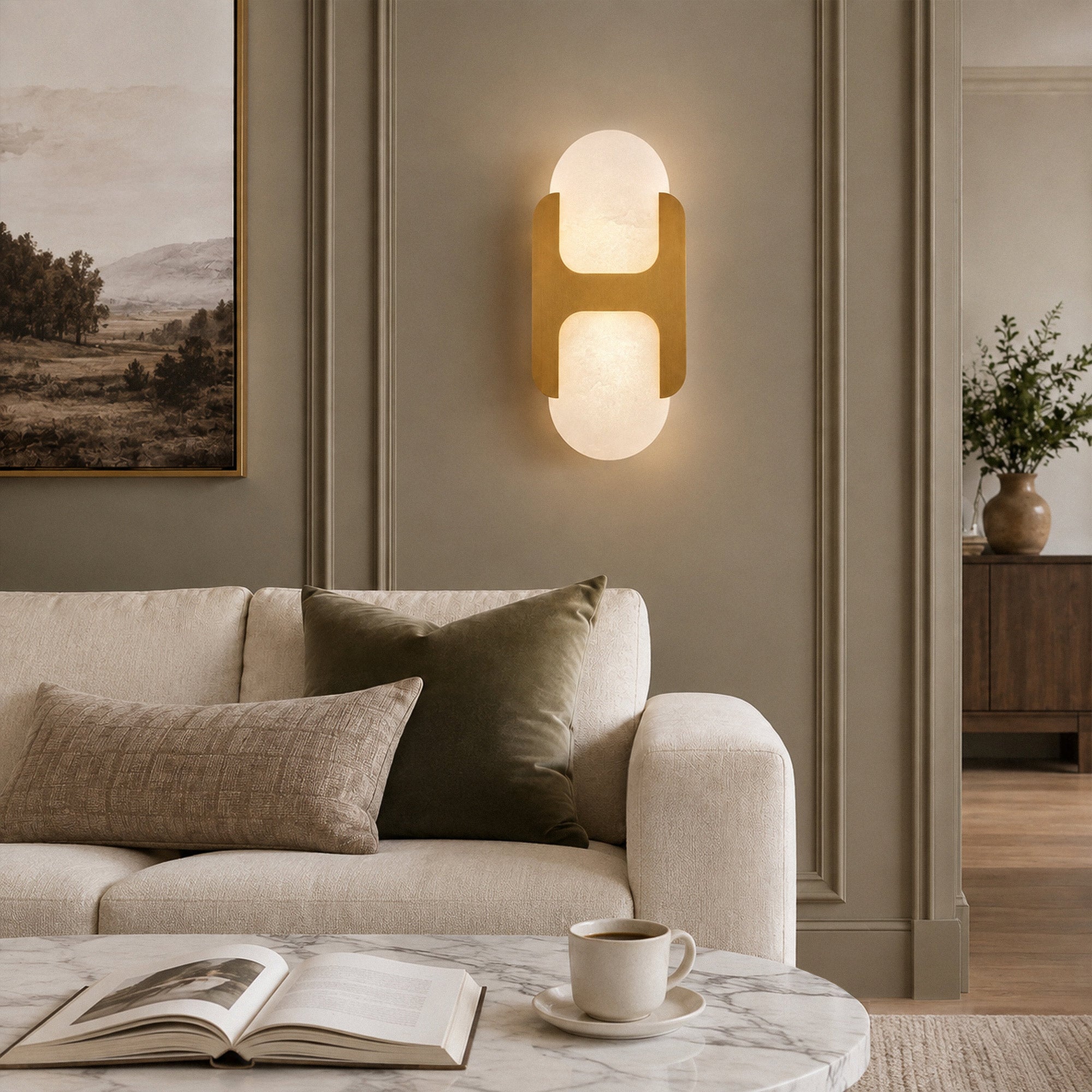 Illuminated H-shaped brass and Spanish alabaster wall sconce mounted on the wall next to a cozy beige sofa in a modern living room