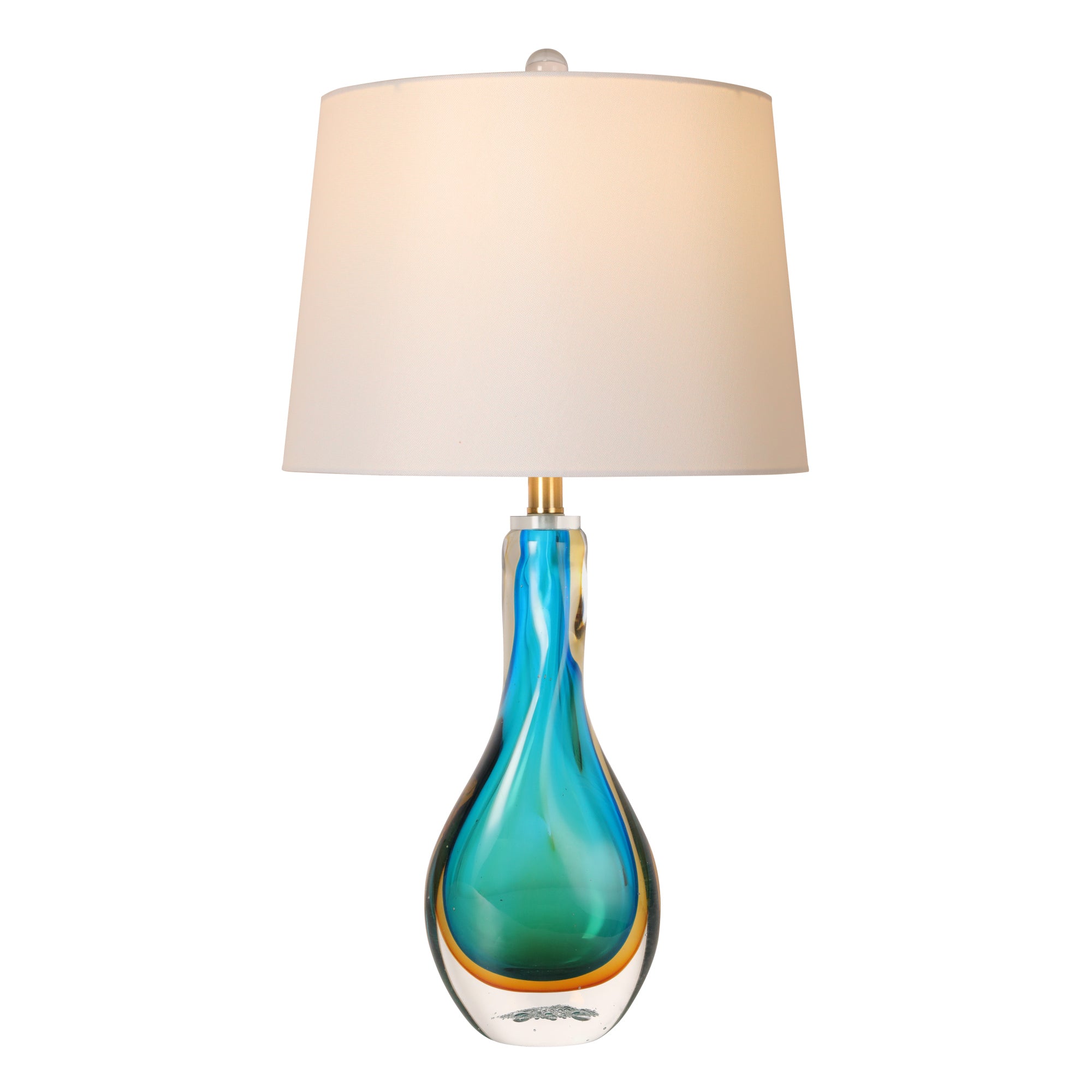 An illuminated multi layer luxury glass table lamp with a bright white drum shade glowing beautifully to highlight translucent blue and amber gold liquid wave patterns inside.